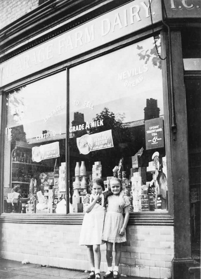 1938 Megan Lloyd and her friend outside the Vicarage Farm Dairy shop in Kew Road, Richmond. Megan's parents were the owners of the dairy business. They had moved to London from Cardiganshire to work in the milk industry.(Courtesy Megan Hayes, Peoples Collection Wales)