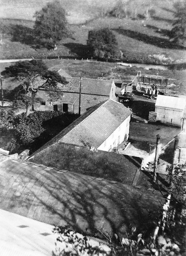 1940's or earlier. Margaret Lycett comments "From the back of the Dairy, School Road runs through the middle of the picture and the buildings on the other side of the road are on the site of what was the Dairy car park, before the Doctor's Meadow development. John Lycettt thinks that the churns are probably filling up with water. Before mains water came to the village in the late 1950's, water in churns was delivered to some houses in the village whose wells had run dry, which I'm told, was due to the Dairy drilling a deep well for their own use much earlier. The sandstone building that still stands is two thirds down on the right hand side of the photo." (Courtesy Margaret Lycett, Ruyton Revisited FB Group)