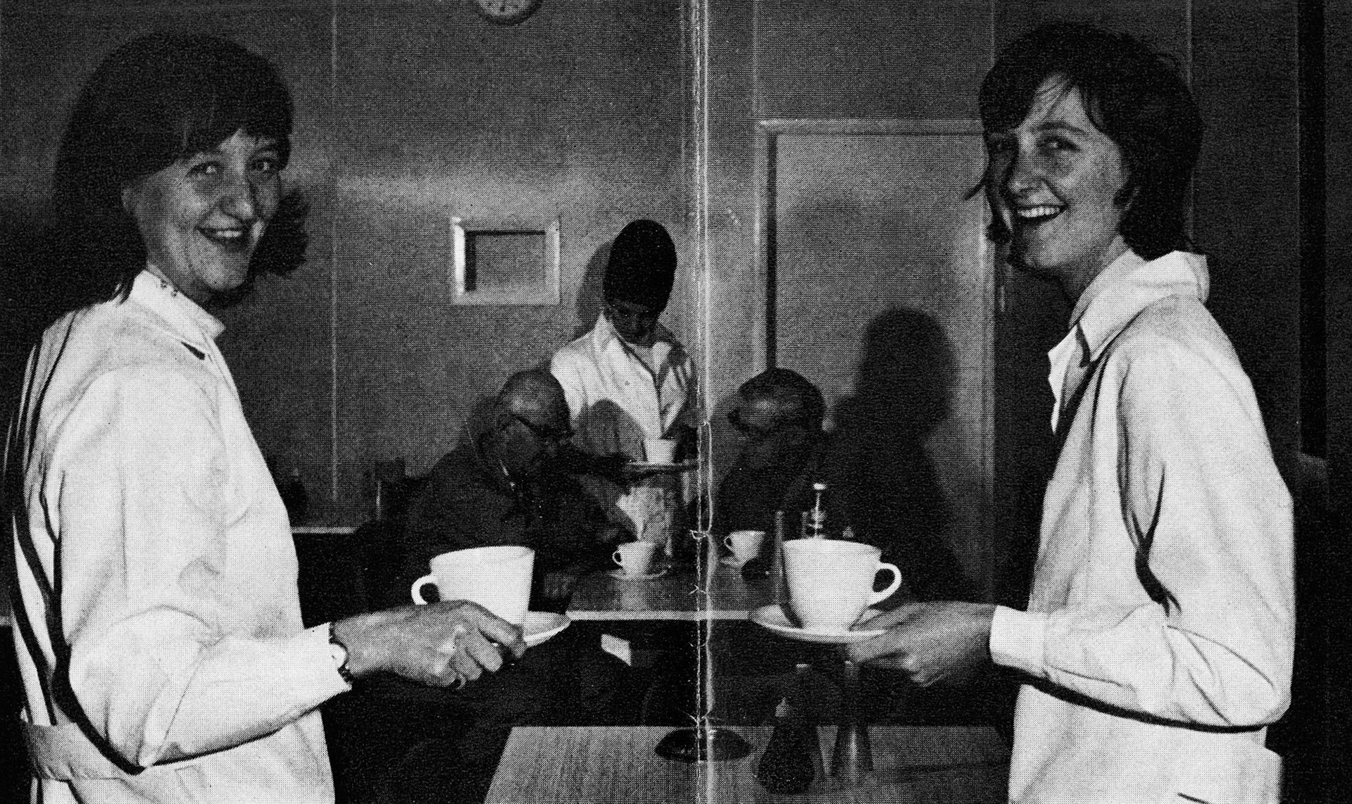 1976 Bradford. Two Hebron sisters pictured in the diminutive canteen. Jean, the younger (left), supervises the Lab with Dorothy (Mrs Pipe) as a part-time underling. In the background, Stanley Sparks, with a mere 48 years to his credit, shares a table with Chief Engineer Harry McMahon, while canteen assistant Mrs Maureen Gill hands out an inexhaustible supply of tea. Diane Allen comments "Yet more memories unlocked-Jean Benson (nee Hebron) was in charge of the lab when I started there, with her younger sister, Margaret, as her deputy. Loved the Kelly brothers, all fantastic people." (Express News Christmas)