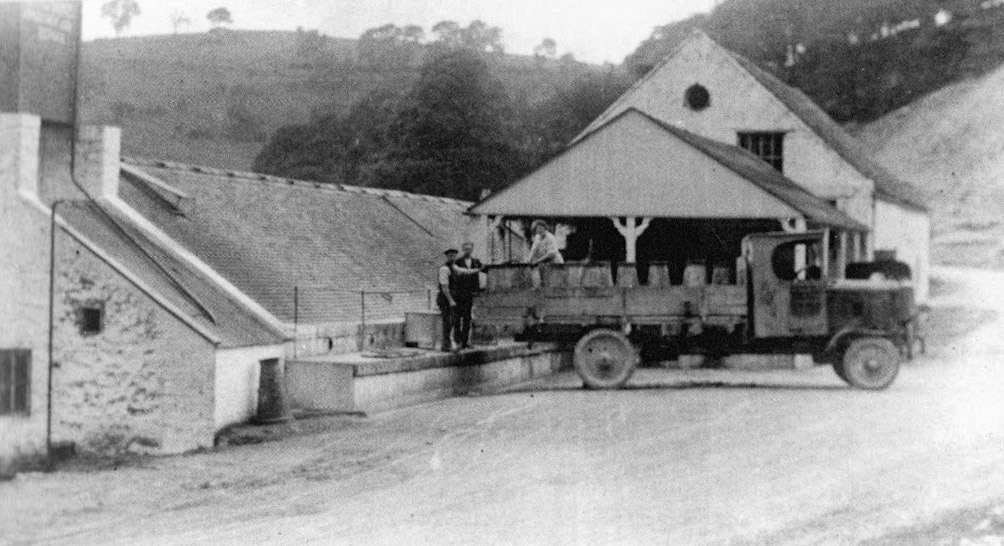 1930's? Ecton Cheese Factory. Alan Salt comments "Churns being delivered, or picked up-parts of the concrete dock remaining now are about the only sign there was ever a dairy there." John Irish adds "The building to the rear with the circular opening in the gable is the former 'clock house' smelter from the Ecton copper mine workings. This formed the basis of the dairy when first opened by F W Gilbert." (Courtesy Alan Salt)