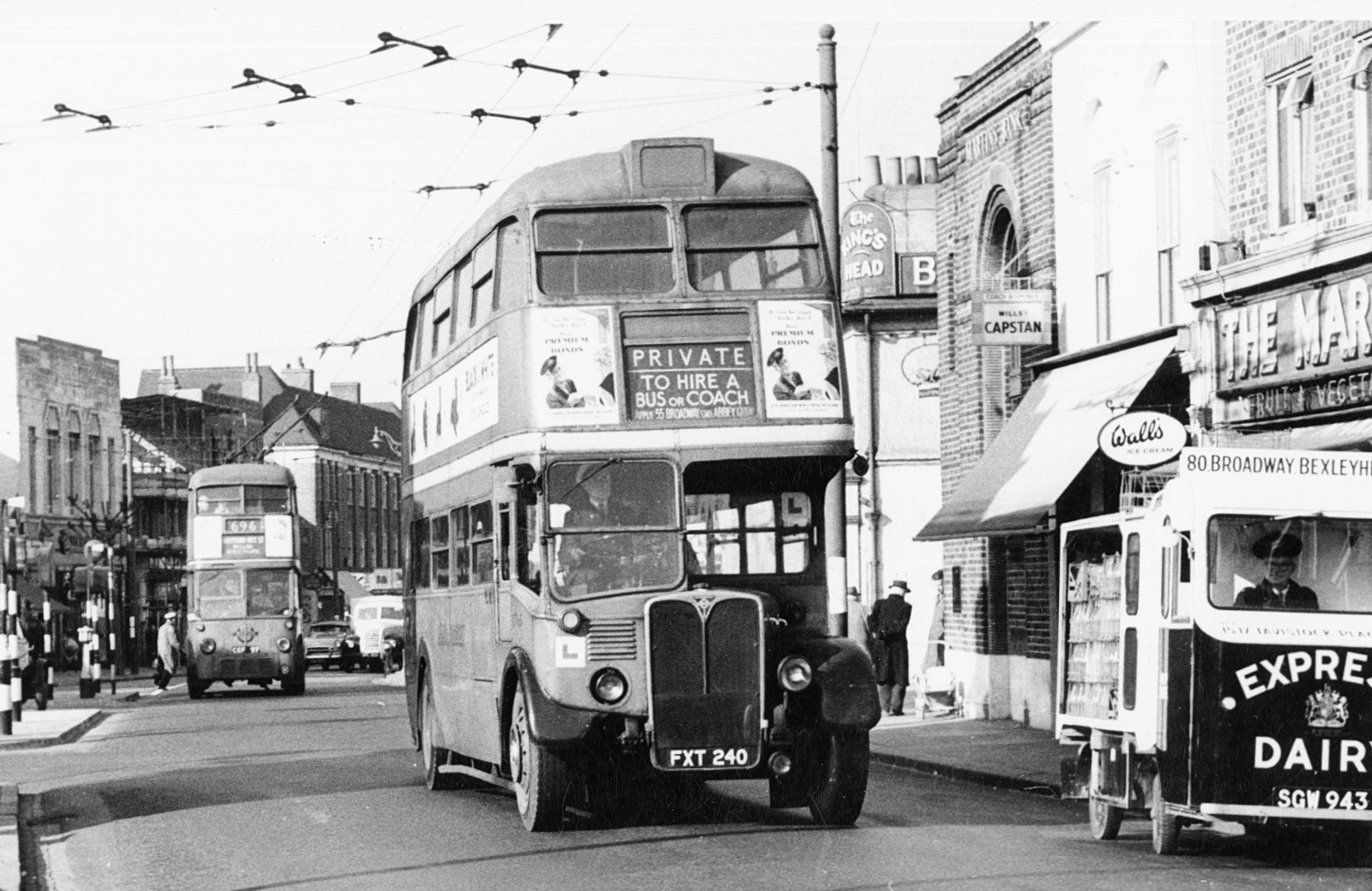 1950s? Bexleyheath delivery float SGW 943, with trolleybuses still in action-Trolleybuses were officially discontinued in Bexleyheath on March 3, 1959. Bexleyheath was one of the first casualties of London Transport's trolleybus abandonment program, and local routes (such as the 696 and 698) were replaced by diesel motorbuses the following day.. (Courtesy Dave Fane)