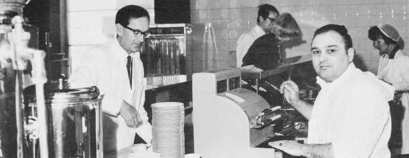 1969 Goldhanger Fruit Farms. From the house magazine of Cadbury Schweppes who had just acquired Goldhanger Fruit Farms. "Canteen, with manager Ken Wood-Ward and unknown female canteen assistant. The employee paying for his food is Gerry Monaghan, who was in charge of the costings office." (Courtesy Lee Morrison)