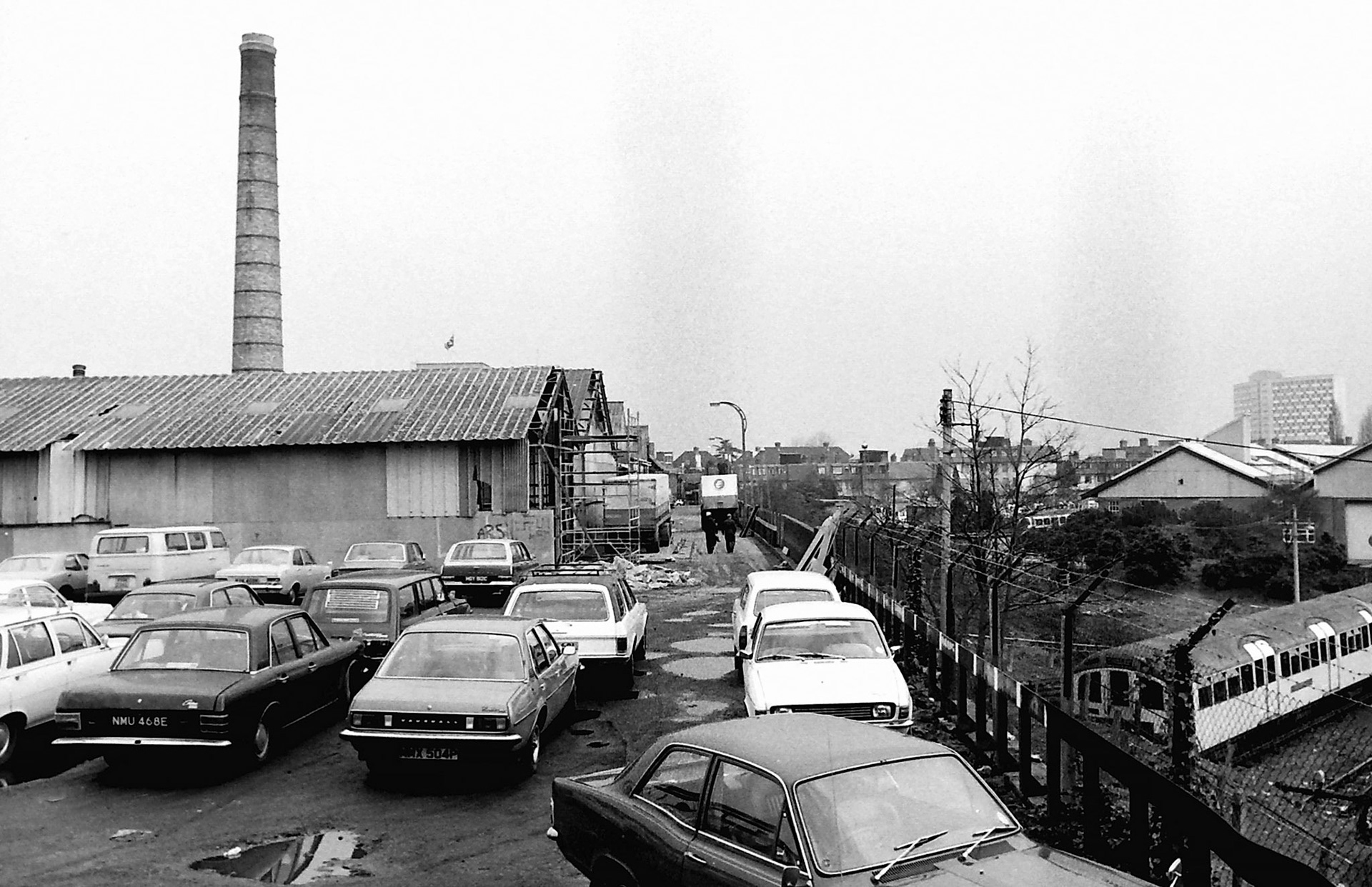 1979 South Morden. View looking North along the side access road adjoining the London Transport sidings. The old boiler chimney awaits demolition. (Photographer Sam Jones)