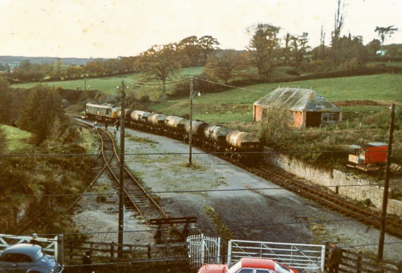 1970s? Hemyock, Devon-A diesel locomotive and a rake of milk tanks stand on a siding, after the station had closed. The station building and platform were in the centre of the photo, with the cattle dock siding to the left, overgrown by this stage. Amyas Crump comments "I suggest it’s the last train, leaving." "Express only did egg packing at Hemyock, the dairy later became St Ivel. (Courtesy Discovering Devon, Somerset and beyond FB)