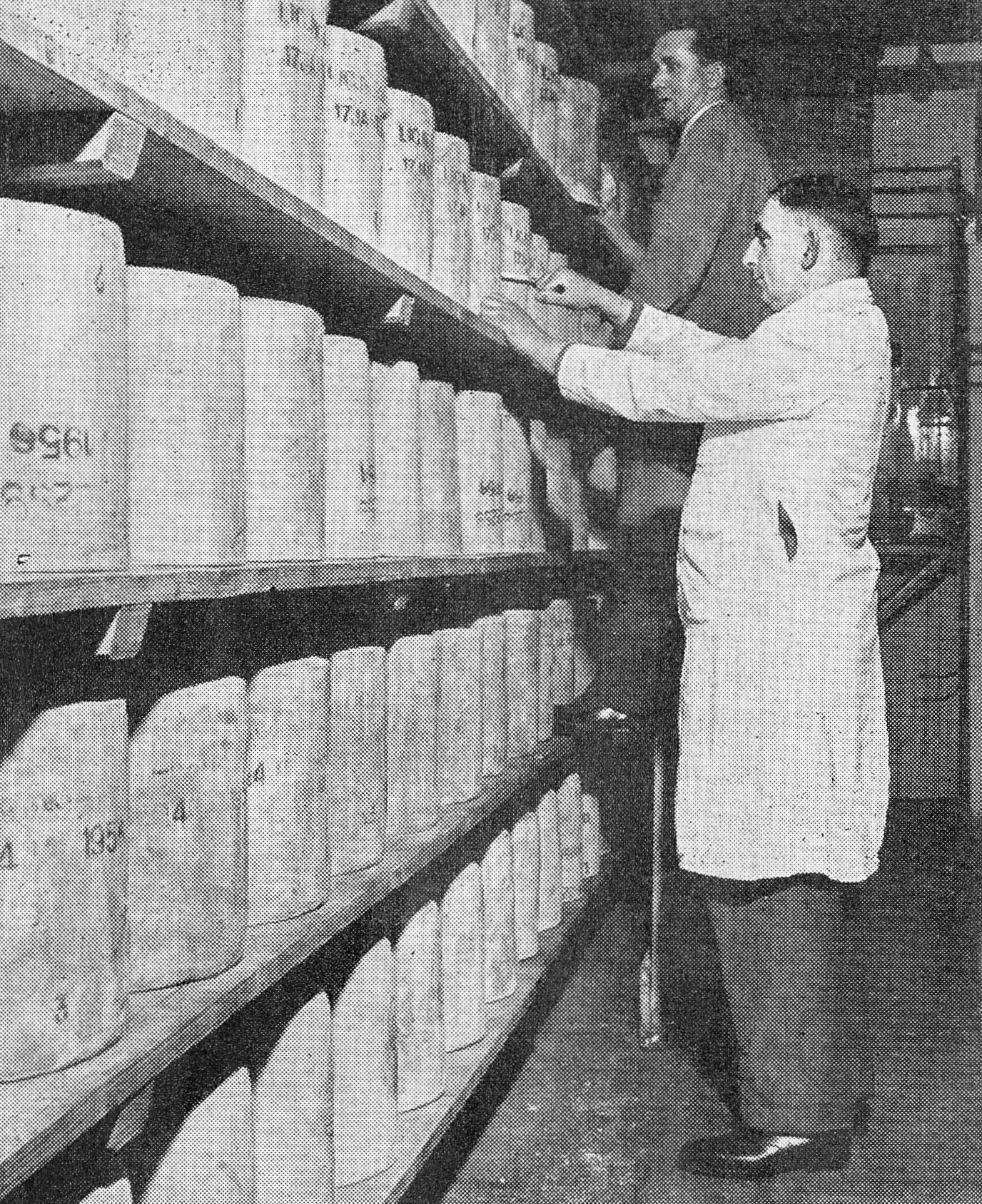 1956 Rowsley Creamery. Mr H.O. Evans (Assistant Manager) bores a 56lb Cheshire cheese. Behind him is Storekeeper Mr Stan Marsden. (Express News April)