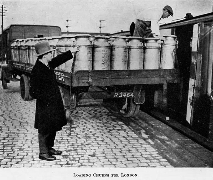 1933 Loading Churns for London. Matthew Pinto believes Uttoxeter. Alan Salt comments "I'm pretty certain it's Uttoxeter-you can just make out "Wilts United Dairies on the truck and the end of the word Uttoxeter-I also think the man pointing is Mr Dainton who was the Creamery Manager." Illustration from 'The Milk Trade, A Comprehensive Guide to the Development of the Dairy Industry' edited by C Raison (Virtue, c 1933).