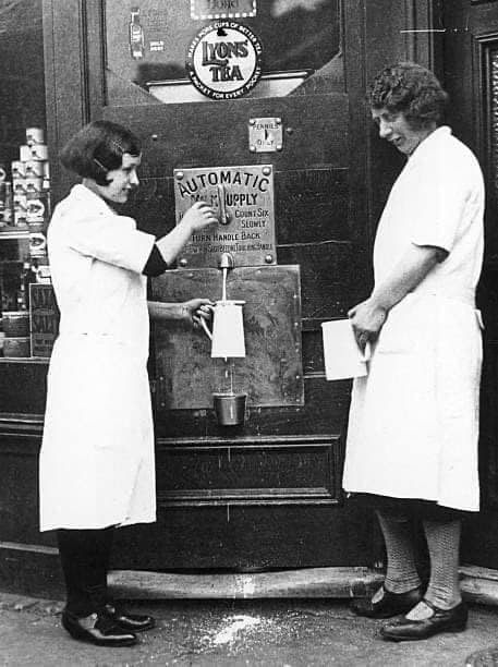 1933  "Two women filling jugs at a milk vending machine, 18 February 1933. Milking the 'iron cow' at the Putney Dairy in London. By placing a coin in the machine it is possible to obtain a desired quantity of milk after closing time'." (Courtesy Ann Cator)