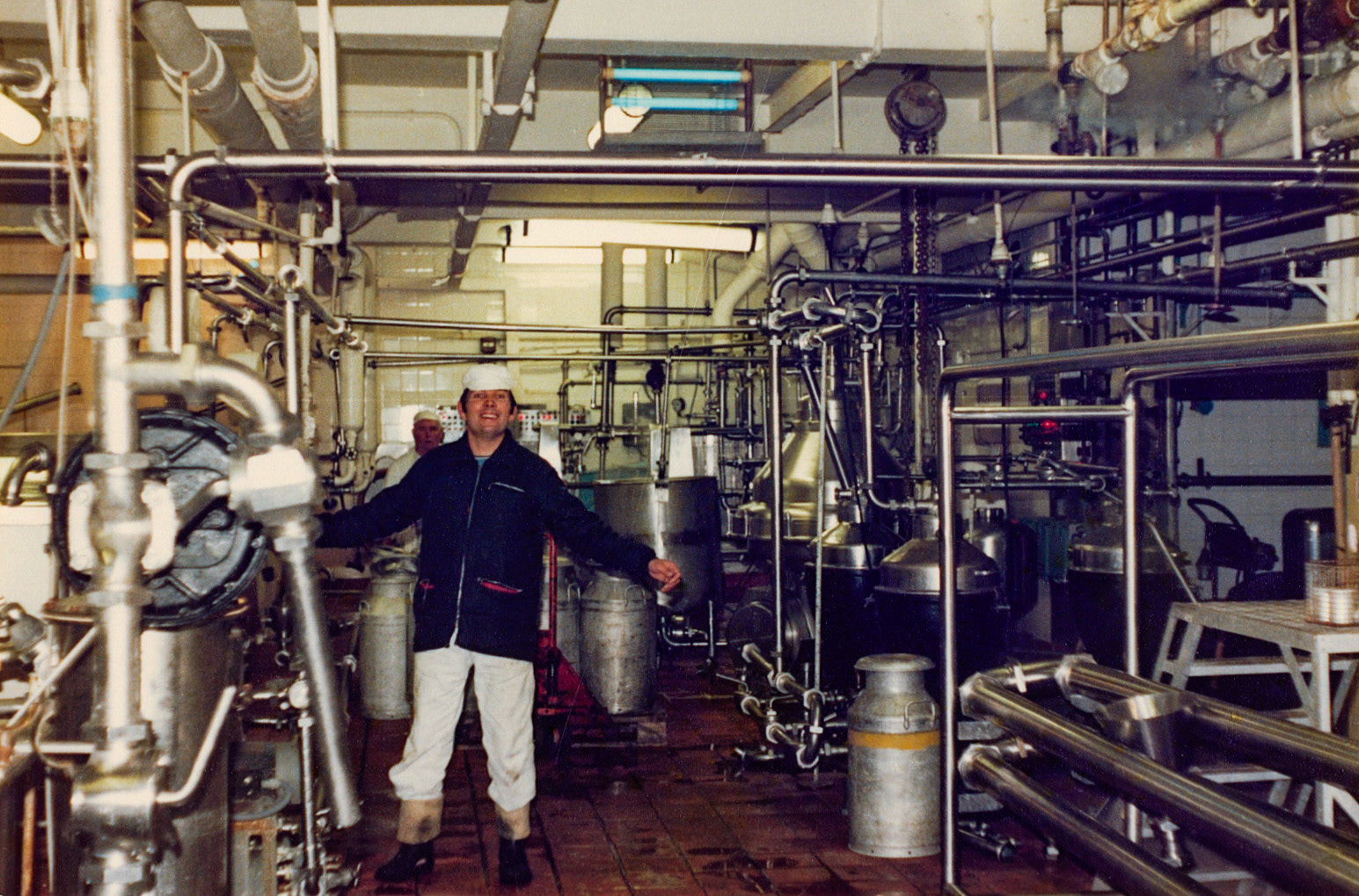 1978 Minsterley. Roy Jones, identified by his daughter, Sarah Smith. Dave Jones commented "It was my job when I was a young lad to paint the yellow band round the top of the churns! I started working at Minsterley when I left school in 1977. Churn collection had stopped a year or two earlier but the churn washer was still used when I started-I can hear it now clunk clonk, and was used most days. The churns were used throughout the factory for all sorts of jobs, so our boss told me to paint the ones we used yellow so no one would take them. Harry Evans adds "Looks like Jim Telford at the back." (Joe Lyons Collection)”