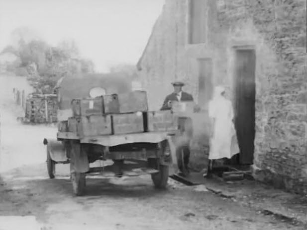 Milk Production Story (1920-1930) - from the cow to the baby's bottle. British Pathé. Handing wooden crate to a driver, who loads it onto back of truck and drives away.