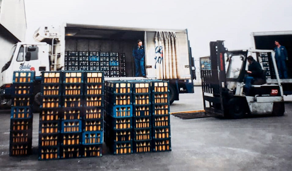 Tarvin. Andy Neville suggests "Mal Harding standing in the truck on the left". John Glaister comments "Dave Davies on the lorry on right hand side, "It was a maximum load of 19440, so you would load  4 x 1080 and 12 x 1260 otherwise known as 4 x 6's at the front, followed by 12 x 7's, Pergals were 40 to a pallet max, 4 pinters were 57 to a trolley. I still remember the stack sizes, used to be 720 and 840 and then changed to above which is 1080 and 1260 otherwise known as 6 and 7's due to the height of the stacks. I still have my homemade card to work out the best formula to load the artic's with milk....sad I know. (Courtesy John Glaister, Old Tarvin FB Group)