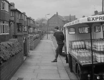 1965 film "Cup Fever". "Children from Barton United are trying to win the local league cup but a local Councillor does his best to ensure that his son’s team wins instead. Skipper and Rocket talk as they help deliver milk. (Naysmith Road in Eccles, with Roby Road and high rise blocks off Cawdor Street in the background.) Rocket delivers more notes advising of the location of the next match. (Shaftesbury Avenue in Eccles) The milkman is asked to help. (Parr Street at the entrance of Lewis Street School with the rear of properties on Renshaw Street forming the background.) A third milkman is asked to join the hunt. (Lewis Street in Eccles) The milkman drives Stopper to the ground. (Edison Road with Shakespeare Avenue to the left.) The floats come to a stand and the missing players rush towards the ground's entrance. (Golf Road with buildings on Moss Lane in the background.) From: https://www.reelstreets.com/films/cup-fever-childrens-film-foundation/