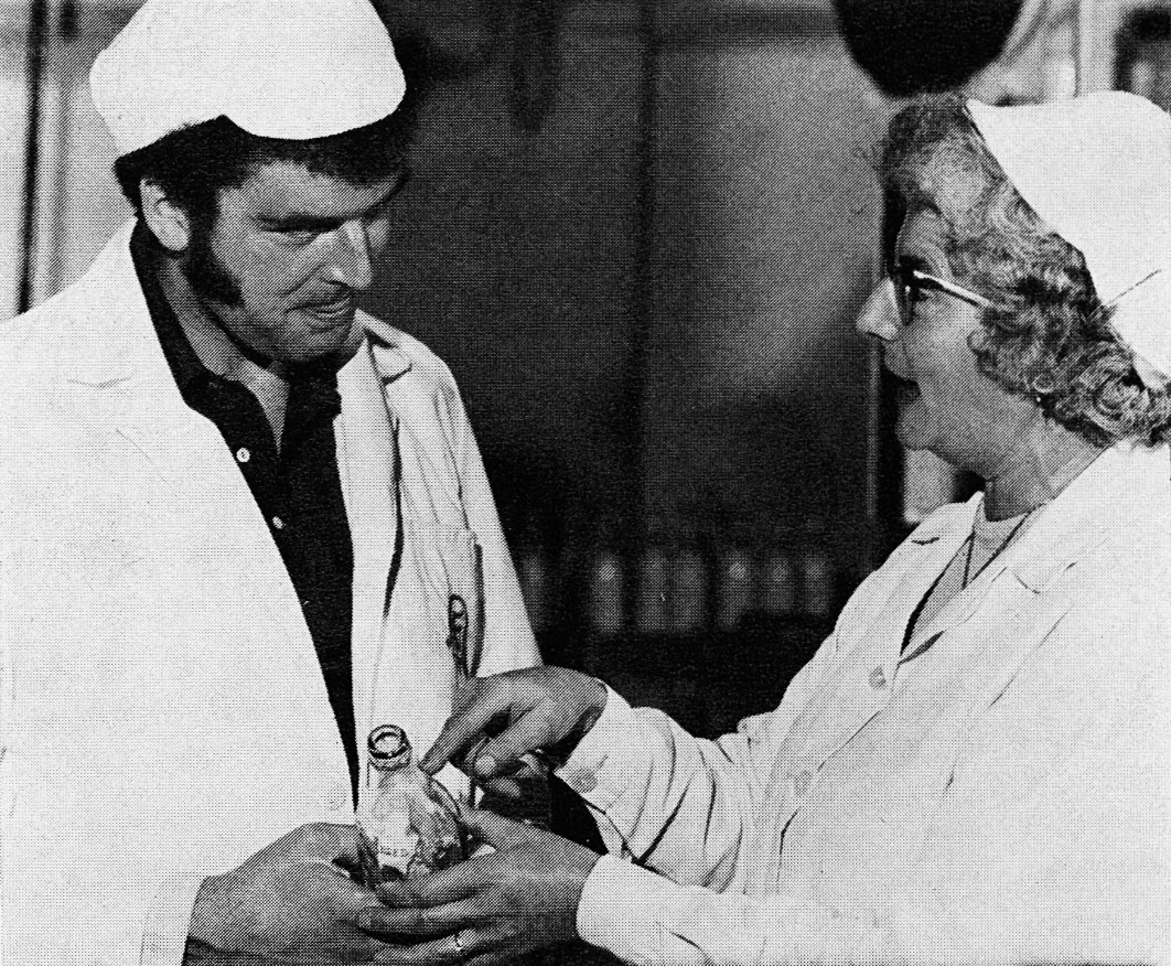1976 Mrs Edith Manley joined us in 1962 as a crater. Now a scrutiniser, she was appointed the depot's Union representative 18 months ago. In our picture she is seen handing over a CWS 'stray' to Dennis Kelly, an enthusiastic rabbiter when not in day-to-day control of No 1 Dairy. (Express News Christmas)
