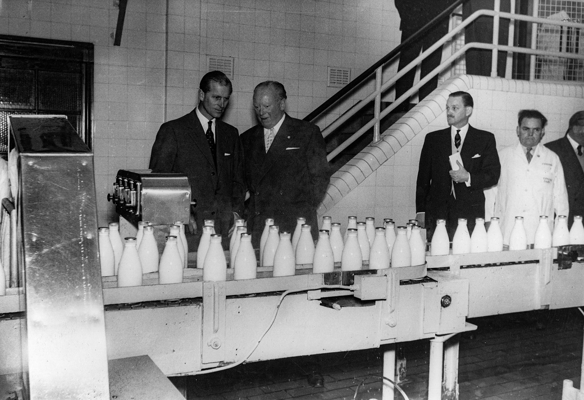 1957 South Morden-Duke of Edinburgh's visit on November 12-filled bottles heading towards the recrater. Mr Ted Legate in the white coat on the right. (Courtesy Paul Luke)