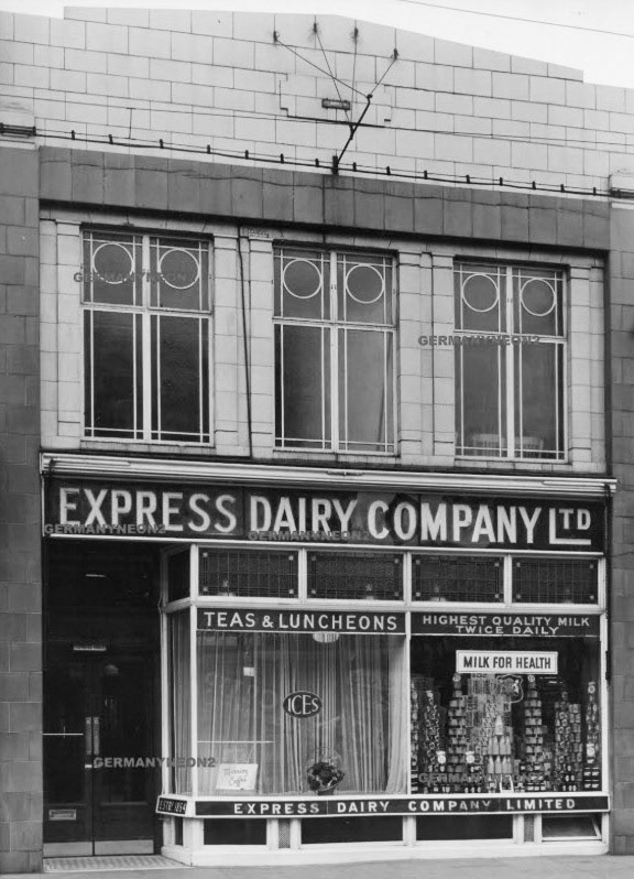 1950's Uxbridge Shop at 22 High Street, from eBay. The seller comments "A fascinating image of a bygone Uxbridge High Street. I spent a happy half-hour travelling up and down Uxbridge High Street on Google Street View.  The level of change between vintage high street and modern high street is quite incredible - Place a 1950's resident in todays High Street and they'd think they were in a foreign country. The plot where '22' should stand looks nothing like the building here. Interesting to see a small plaque on the very top of the building which reads 'Claudgen', a manufacturer of Neon signs from the 1930s, and later taken over by GEC. It looks like the upper part of the Express Dairy was once illuminated with advertising signage". Richard Gaylard comments "The retail outlet I remember as a ground floor shop which latterly became a “Premier” supermarket with a restaurant/ café/tea room on the first floor."  (eBay screen grab)