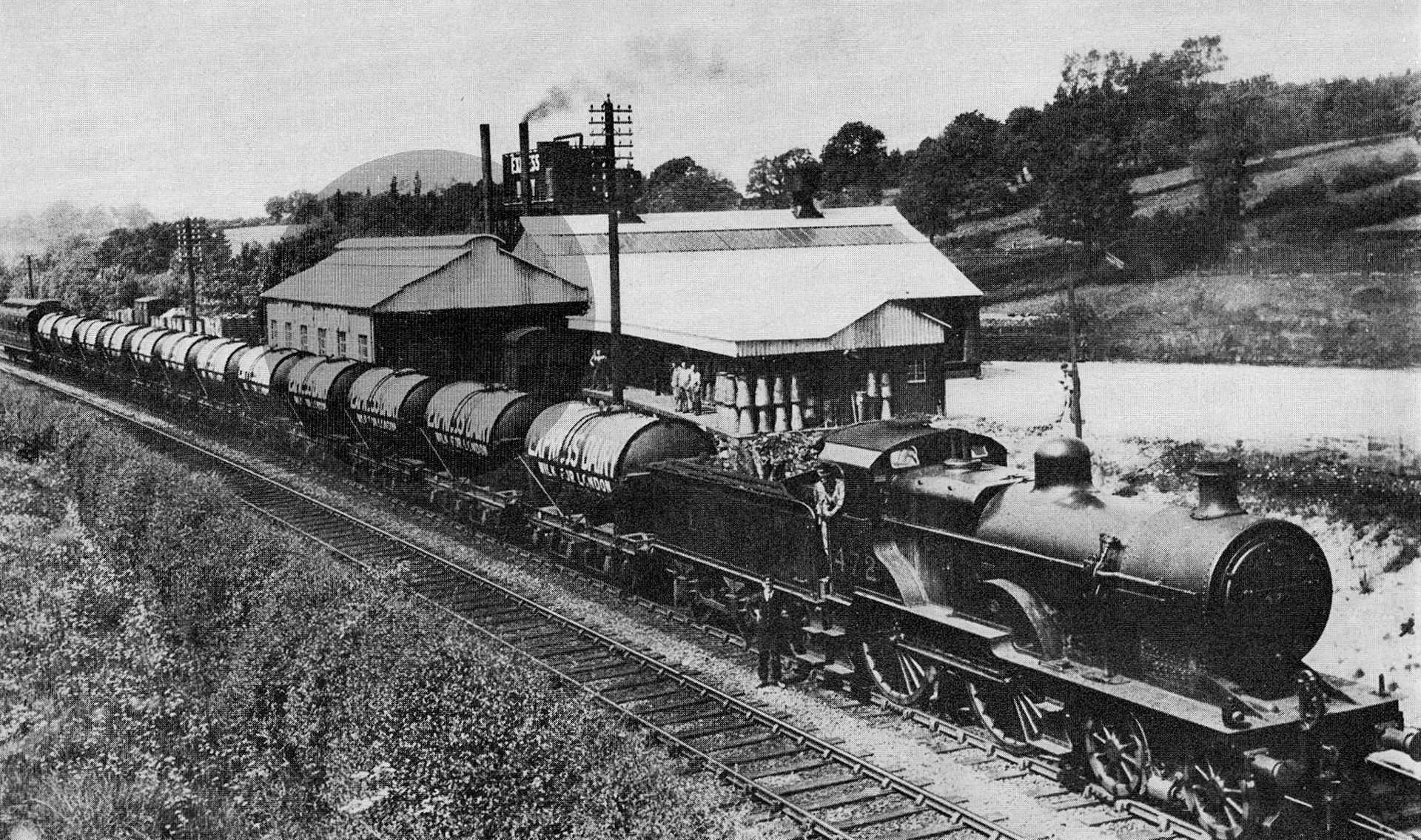 1931 Appleby Rail Siding, reproduced in Express News Christmas 1975. Locomotive 472 pictured is an LMS Class 2 designed by George Ivatt, originally built from 1884 - 1901, and rebuilt in this form between 1912 and 1923. Darwin Smith comments "Most milk trains were run at Express Passenger speeds. The first milk tank wagons built in the 1920s had four wheels. Following some derailments it was decided that these were unstable at speed and milk tanks began to be built with six wheels. Eventually older four wheel wagons were all rebuilt to have six wheels. The first six wheel tanks built for the LMS were delivered in 1931. The picture may well be posed to show these new wagons. (They are all very clean and the number of wagons would probably have been the total number delivered for Express Dairies use in that year. Further wagons were delivered in subsequent years and older four wheeled wagons were converted to have six wheels.)"