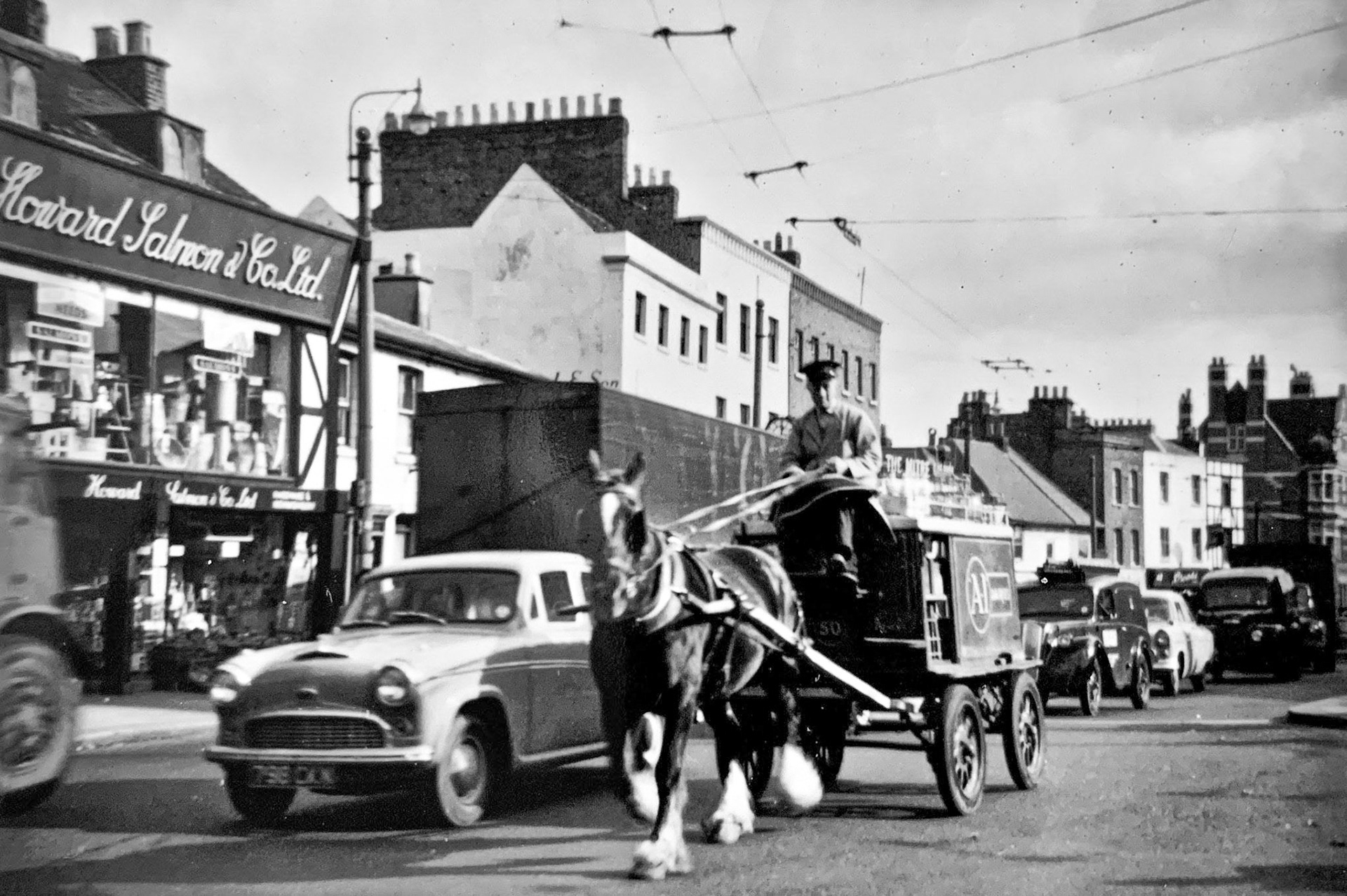 1960's A1 Dairies Whetstone-horse and delivery cart in the High Street. David Ewen comments "A1 Dairy was green and white. I was a milkman's lad delivering milk and shovelling up horse droppings, tipped into a sack hanging off the back of the cart! Great days!!!". Steve Dommett adds "Our milkman Harry delivered by horse and cart in Bells Hill around 1960. My job was to collect the manure (from the horse not the driver) for my grandad (not for him but his rhubarb). Harry wore the full leather apron and leg gaiters. I was about 5 years old." (Courtesy Terry Betty Levy, WHERE HAVE ALL THE BARNET PEOPLE GONE FB Group)