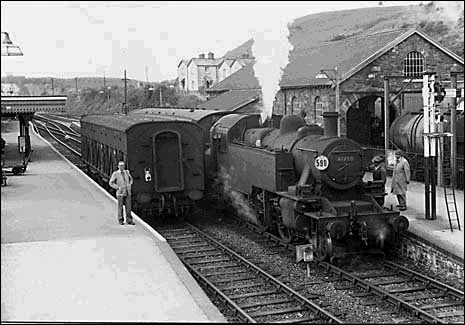 1956 August, 41298 at Torrington on the 4pm service to Halwill Junction. The tankers for the 4.37 p.m. departure are being loaded behind the goods shed and the van for that train waits at the platform. Photo: Peter Gray.