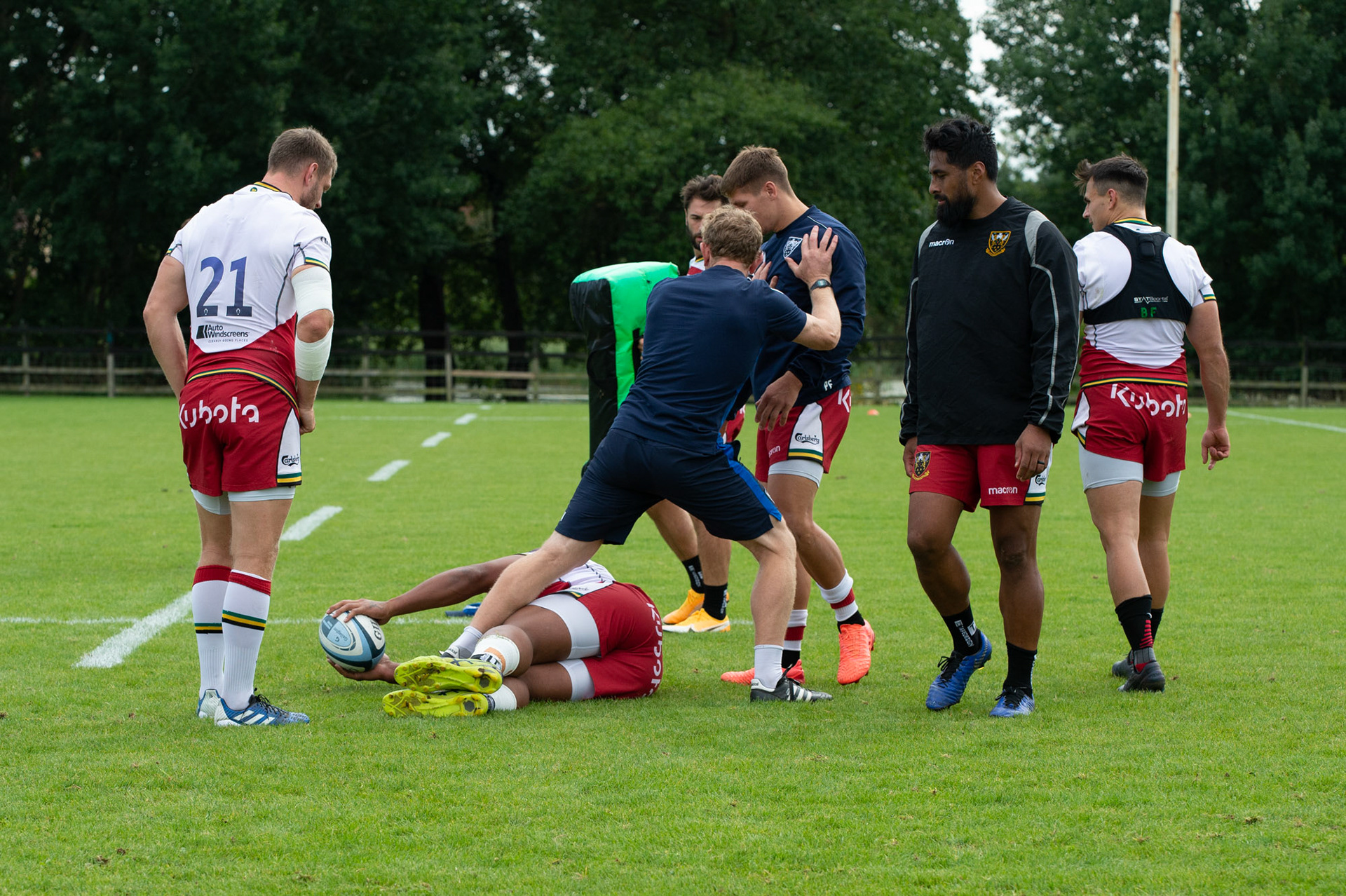 Attack Coach Sam Vesty  middle in blue at Training Day for Northampton Saints  at   Franklin's Gardens  as  Ahsee  Tuala  in blue boots looks on .