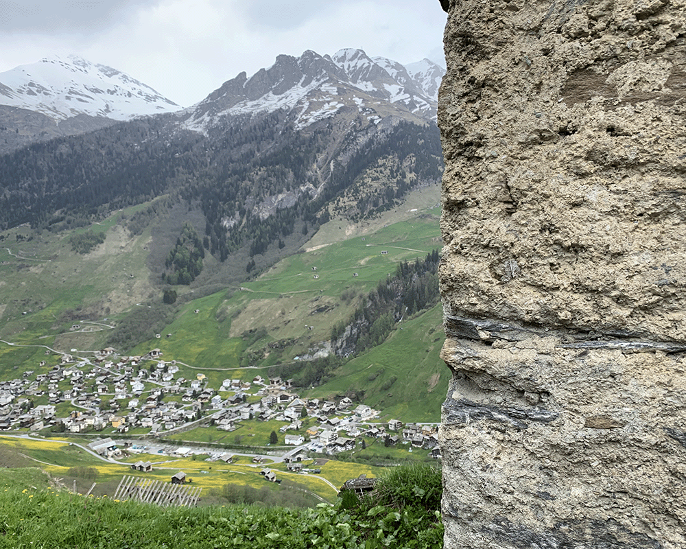 Vernacular farm hut sheep shed exterior wall made of stacked local stone and mortar in Vals, Switzerland overlooking the town in the lower valley with snow capped mountain