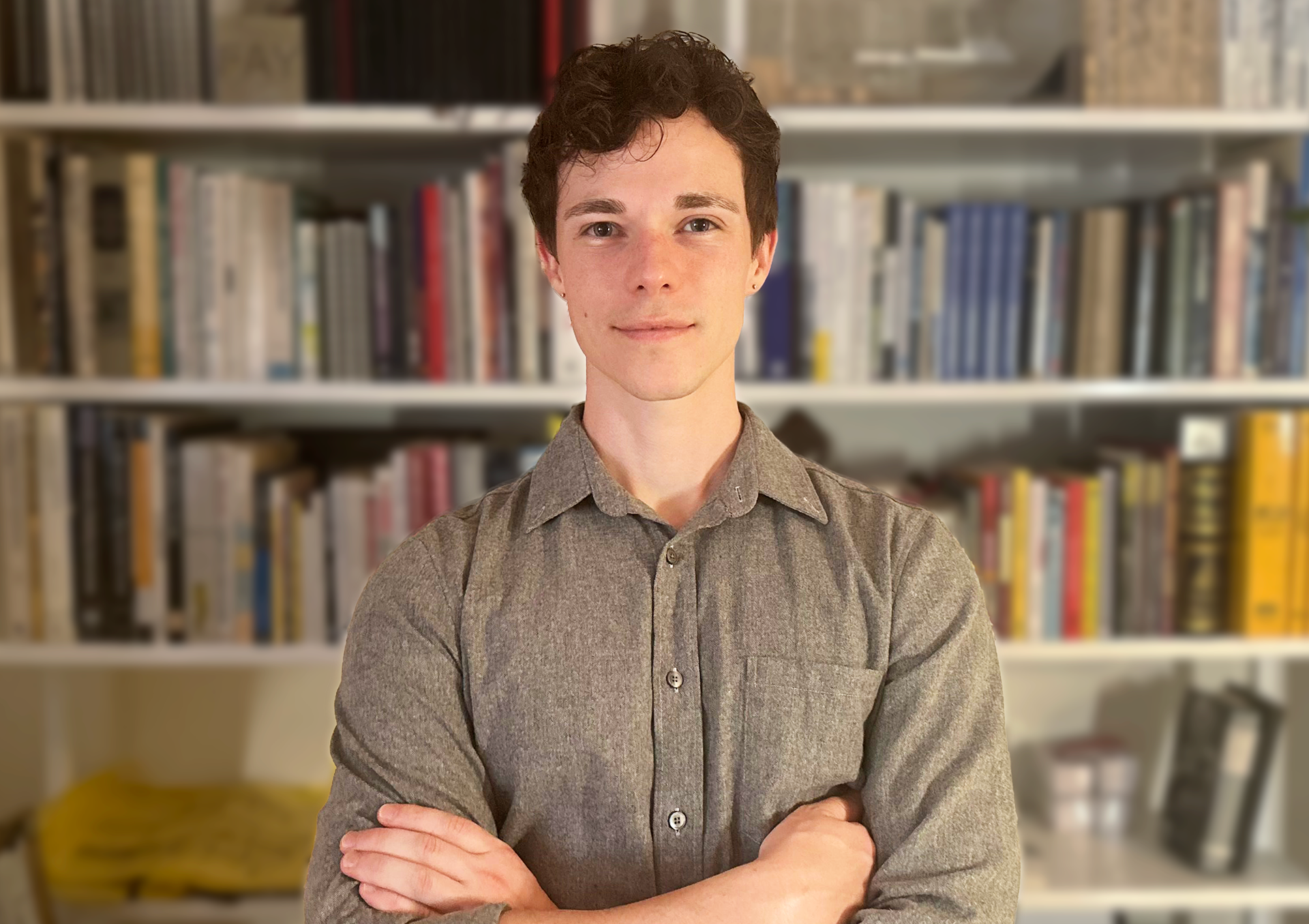 David Sweere, AIA, NCARB standing with crossed arms in front of a book shelf and architectural models.