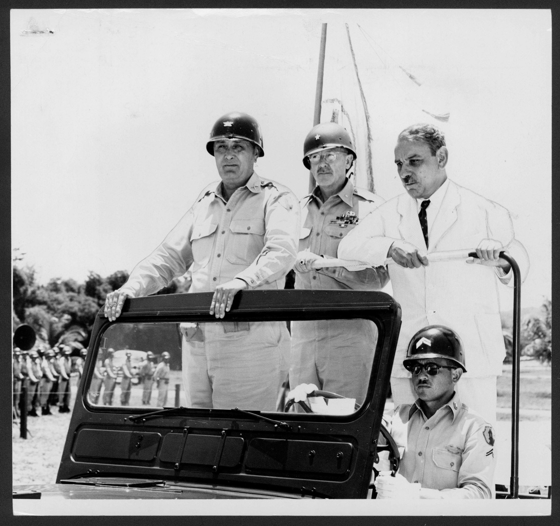 Coronel Traywick, General Sweary y Gobernador Muñoz Marín, de pie en un jeep, pasan revista a tropas.Campo Toruguero, Vega Baja.1954