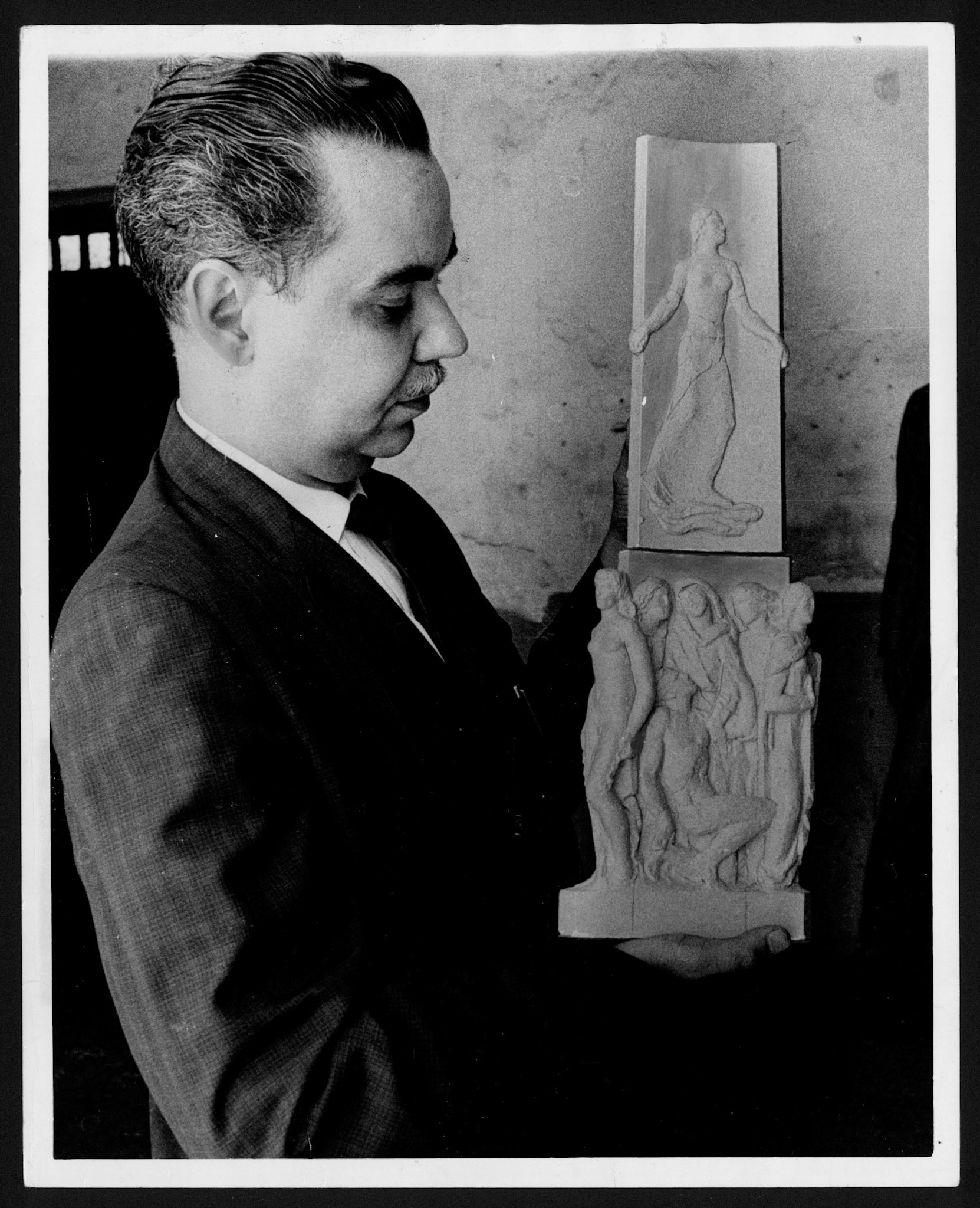 Ricardo Alegría sosteniendo en sus manos esculturas de figuras humanas.Octubre 16, 1967