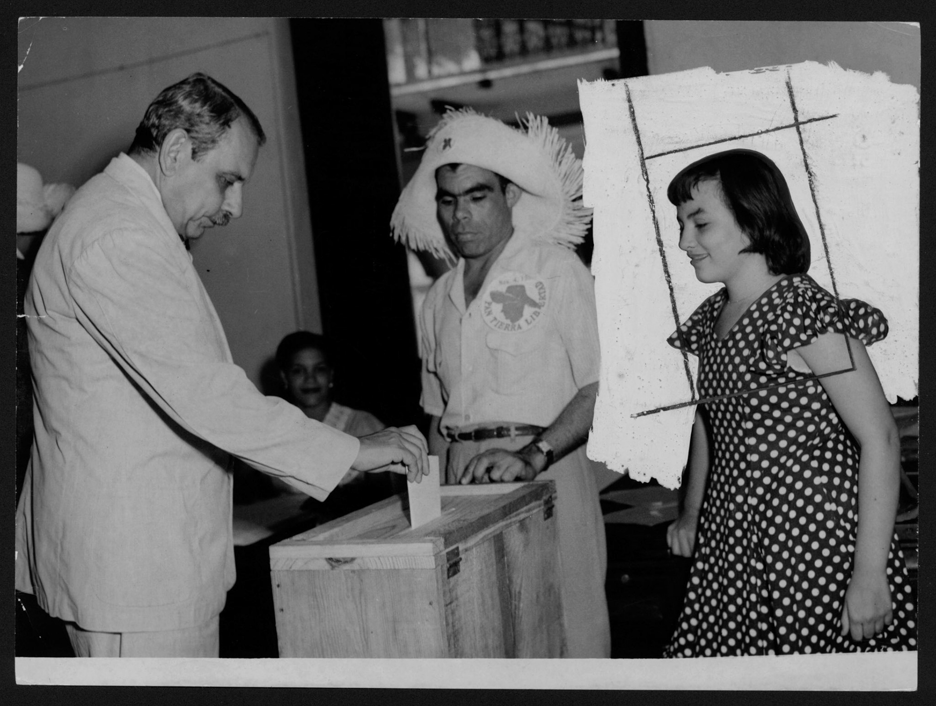 Luis Muñoz Marín depositando su voto electoral en urna frente a su hija Victoria y un funcionario del colegio.Noviembre 4, 1952