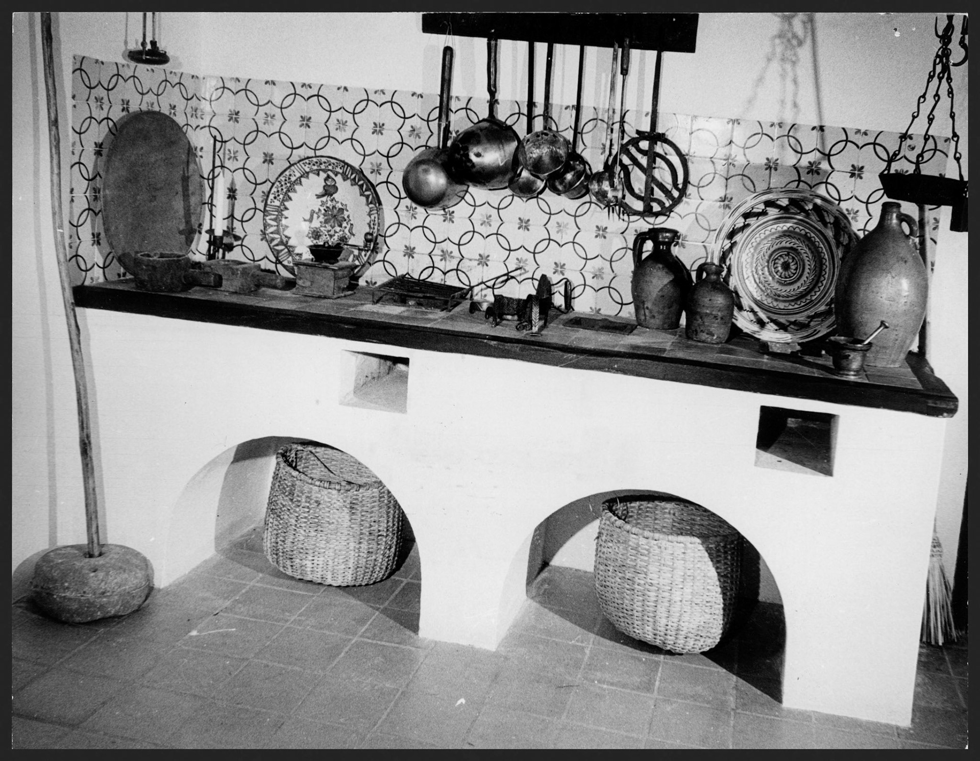Información: El Mundo, 9/ene/1965. Pie de la foto: De la pared penden los cucharones y cazos, y hay sobre el fogón planchas de calentar en carbón.Enero 9, 1965