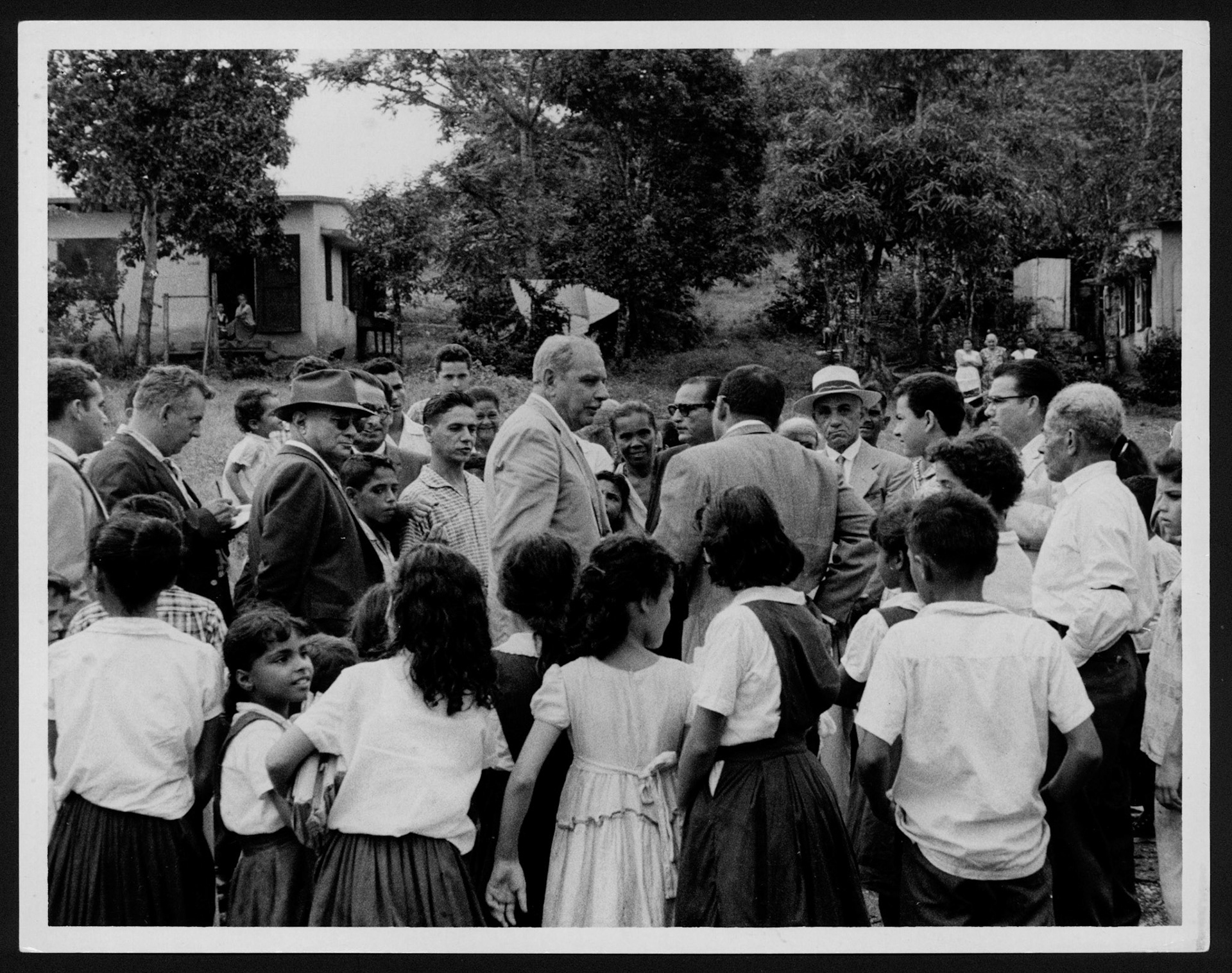 Gobernador Muñoz Marín rodeado de escolares, vecinos y ayudantes en el caserío semi rural José Mercado, en Yauco.1962