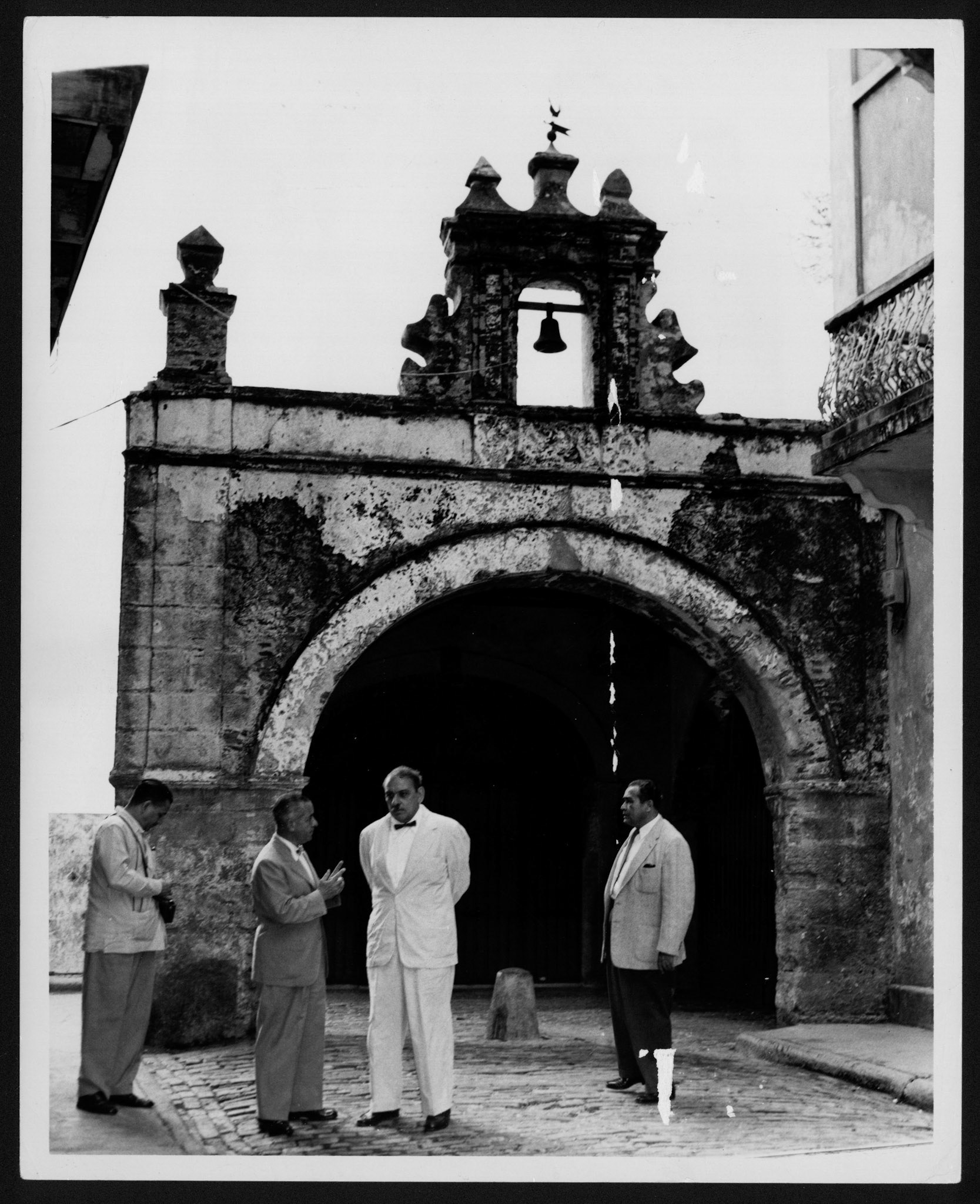 LUIS MUÑOZ MARÍN ACOMPAÑADO POR TRES SEÑORES FRENTE A LA CAPILLA DE EL SANTO CRISTO.