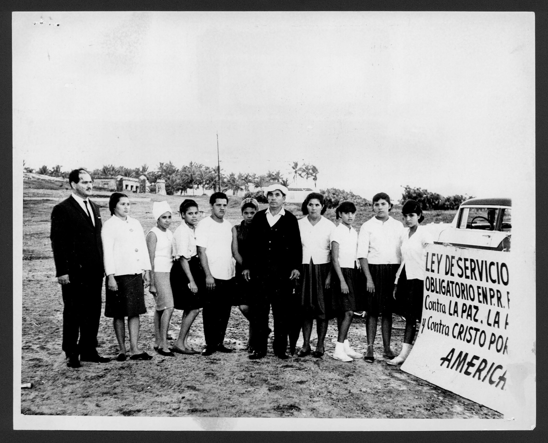 Grupo en contra del servicio militar obligatorio junto a pancarta alusiva a la protesta.Julio 4, 1966