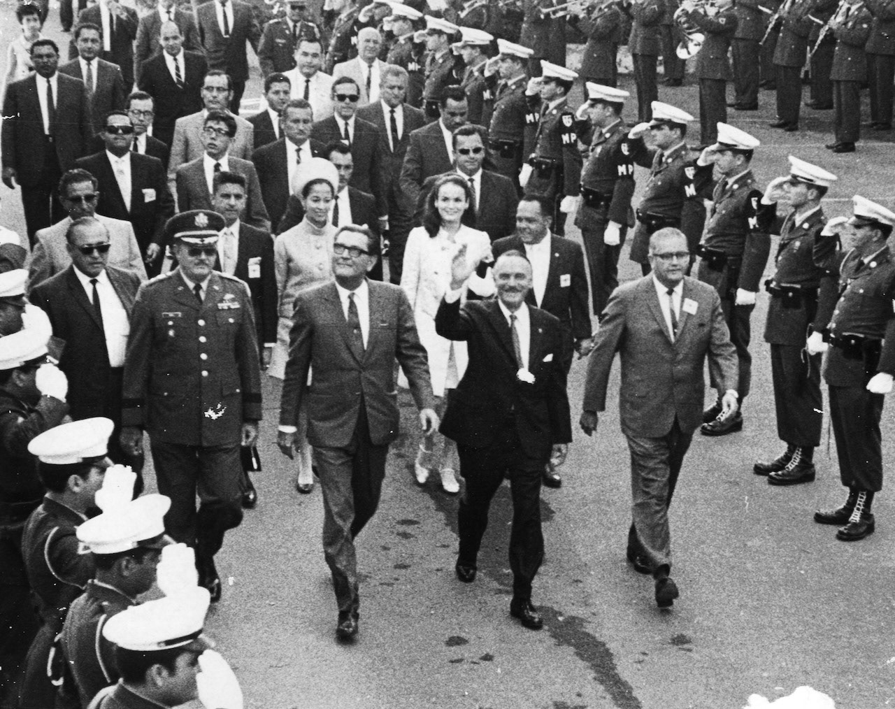 [Luis A. Ferré saluda al público mientras camina junto a Roberto Sánchez Vilella y otros funcionarios.Enero 2, 1969