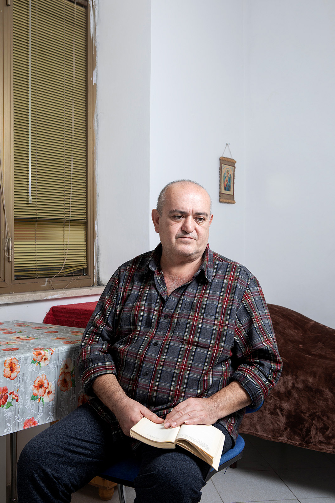 Anagni (FR), Italy, 15 December 2022. Serhii Avanesian, 54 years old, portrayed in the Extraordinary Reception Center (CAS) managed by the Diaconia cooperative in Anagni (FR) where he is currently hosted together with other Ukrainian refugees. Serhii was born in Azerbaijan to parents of Armenian descent and is a spine specialist. In 1991 he graduated in medicine from the University of Baku and in 1992 he had to leave his home in Nagorno-Karabach due to the conflict between the ethnic Armenian majority, supported by the Republic of Armenia, and the republic of Azerbaijan. Together with his wife, also a doctor, he moved to Pyatigorsk, Russia. After about 10 years, following the separation from his wife, he decides to move to Kherson, Ukraine. Li starts working in the city hospital and in his private practice. Serhii reports that he earned well, so much so that he was able to afford to build a house about 30 km from Kherson, where he lived until the beginning of the conflict. His house is located on the left bank of the Dnipr River, in territory currently occupied by the Russian army, just on the road taken by the Russian army from the Crimea. For two months he lived under Russian occupation. Thanks to his financial resources, at the beginning of the conflict he had managed to obtain a large supply of food and basic necessities, which allowed him, during the first month of occupation, not to leave the house. He also started making his own bread, which he shared with local elders and other needy people. He says that throughout the period of occupation the windows of the house shook incessantly due to the noise of explosions and helicopters flying at a very low altitude. After the first month, he began to leave the house to get food. He says that whoever wanted to leave had to display a white flag from the car, a precaution which, however, did not automatically mean safety, given that the Russian army fired indiscriminately in the direction of the cars. Even the soldiers, mainly Chechens or Russians of the Buryatia ethnic group, were very aggressive and ready to point their Kalashnikovs at civilians. In late April, the Russian military released information that non-Ukrainians could leave the country and head for Russia. On April 26, he thus decides to leave his home, for the second time in his life. At a checkpoint between Ukraine and Crimea, during a check, the Russian military connected a device to his phone, discovering that his contacts included two officials of the Ukrainian intelligence services, who were actually two of his patients. For this reason he was interrogated for seven and a half hours in a row. He was later released and with a bus he was able to reach the city of Yerevan and from there Tbilisi, from which he left for Italy. Serhii hasn't seen his daughter since February 20, when she visited him from Russia where she lives in Kherson to organize her wedding, which was supposed to be celebrated in the spring.