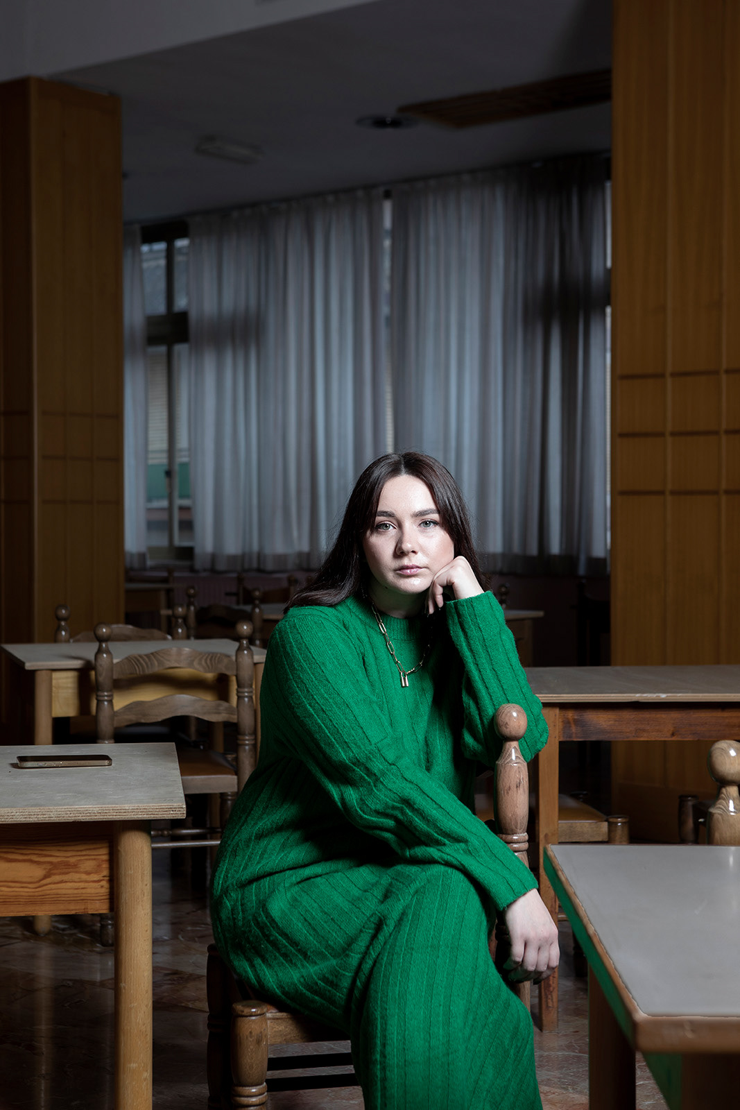 Fiuggi (FR), Italy, 16 December 2022. Yuliia Yurhina portrayed in the dining room of the Hotel Continental where she is hosted together with other Ukrainian refugees. Yuliia is 27 years old and comes from Zaporizhzhia. After graduating in Sociology and Politology he worked as an assistant for a local politician. Before the war he held two jobs: he was the executive director of a coworking (later permanently closed due to the covid) and he worked for an NGO that was involved in tutoring orphaned teenagers hosted in foster homes, to whom through the technique of debate (learned at university days when he had participated in various national tournaments) he taught to develop one's own critical thinking, that is to build one's own opinion and express it. After Covid he oversaw the electoral campaign of a candidate for mayor of Zaporizhzhia. Yuliia reports that she developed her interest in politics at an early age, when her great-grandmother read books to her about the Holodomor, the terrible famine that was caused by the USSR government in the territory of Ukraine from 1932 to 1933, causing several million dead, and that she herself had lived, living on grass and suffering the loss of five children. Yuliia decides to leave Zaporizhzhia only towards the end of April. He says that at the beginning of the conflict he constantly monitored the situation, feeling strong also from his studies, and tried to postpone a possible departure. After learning of the crimes committed by the Russian army in Bucha, she began to fear and for two weeks she could not decide to leave, overwhelmed by the guilt of having to abandon her family, who had decided to stay. It was only towards the end of April that she made the decision to flee and bought a ticket for Lviv with the intention of arriving in Italy, where she had already been three times. After a relatively uneventful journey he arrives in Lviv. From there she took a bus to Krakow, where a friend was waiting for her. He stayed with her for a couple of days before getting back on the road to Rome via Vienna. In Rome, waiting for her was a family from Viterbo that Yuliia had contacted through an advertisement. He stays in Viterbo for a few days, then decides to find an apartment. The cheapest he can find, however, is in Vieste, Puglia. She books the apartment through a well-known portal, but once she arrives there she discovers that the apartment that had been assigned to her is completely different from the one booked. She immediately makes a complaint and the owner kicks her out in a bad way, without letting her stay even one night. After a night spent in a hotel with other refugees, she sets out again for Rome, where this time, however, she turns to the Red Cross, which places her in the reception system and transfers her to a hotel in Fiuggi, where she still resides.