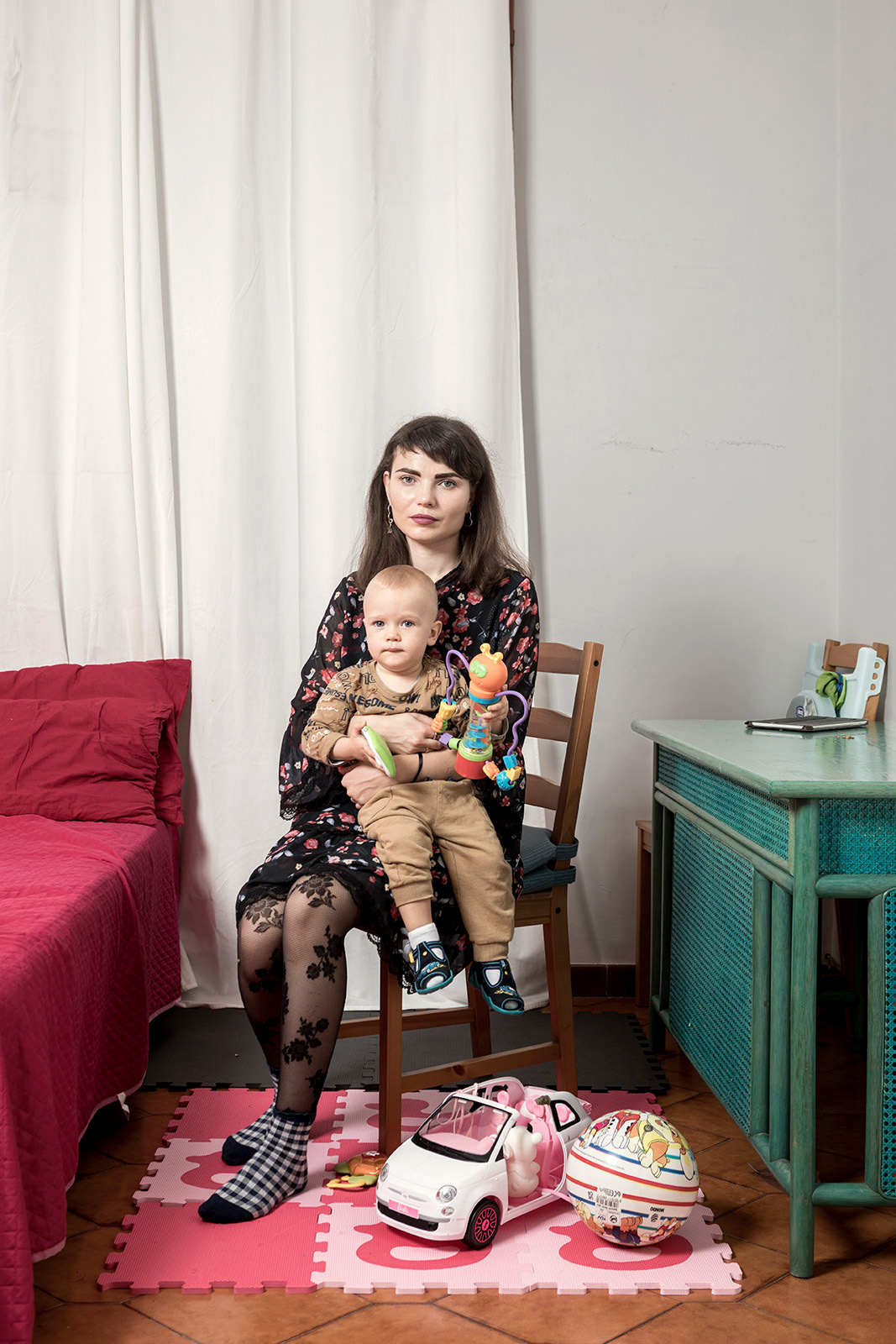 Rome (Italy), 28 October 2022. Daria Demydenko, 29, portrayed with her one-year-old son Svatoslav in the apartment of the SAI Project "Aida Roma" in Roma Capitale (ARCI Roma Aps and Be Free Soc. Coop.), Where is hosted with her 58-year-old mother Svetlana Hoshii. Daria was born in Kiev, raised in Paulograd and then moved to Dnipro. Daria graduated in medicine but was unable to complete her internship due to becoming pregnant. Daria remembers that the day before the start of the war there was already a certain nervousness in the air. When the war broke out, he initially believed it was a terrorist act. Her husband, who was staying with relatives at the time, told her to prepare to flee and that he, as a reservist (he teaches at the military academy and was already called to arms in 2014) would be drafted. Meanwhile, Svetlana from Paulograd arrives in Dnipro with the car used for transporting drugs, which is also ready to go. Daria remembers that the days following February 24 were dramatic: she remembers that on the streets people crowded in long lines to get food and there was a lot of confusion. On March 4, after an attempt that failed due to the huge crowd that stormed the trains, they managed to leave, also thanks to the help of a police officer who escorted them to the train to protect the child. The train was full of people. There was no free space and it was difficult even to go to the bathroom. The child was crying constantly from hunger, since Daria, not having hot water, could not prepare his meals. At each stop people kept getting on. He doesn't remember exactly where he was, but he says that at one point many people came from a country that had just been bombed. Daria also remembers the shooting at the train, which had to go back. Finally, after 24 hours, the train arrives in Lviv, where Svetlana, Daria and Svatoslav first find refuge in the room for women and children up to 3 years old set up near the first platform. Then, on the advice of a volunteer, they moved to another reception center set up near a Catholic church. There, 40 slept in one room, dividing a single mattress in three. They decided to leave for Italy because for France they would have had to pay € 150 each while only those who had relatives there could go to Germany. They manage to catch a bus that was returning to Italy after having brought humanitarian aid. After 35 hours of travel, of which 8 in a row on the border between Ukraine and Poland, they finally arrive in Rome. There they are welcomed by an Italian couple who provided them with all kinds of aid, from shampoo to clothing, and hosted them for 2 days. Subsequently, Daria, Svetlana and Svatoslav are transferred to a hotel, where they remain for 4 months and subsequently the apartment where they are still staying is assigned by ARCI. Daria manages to get in touch with her husband at the front only when the signal is reconnected to him. The husband, for security reasons, cannot tell Daria where he is.