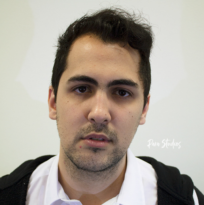 A portrait of Tony, they wear a white shirt and a black jacket.
