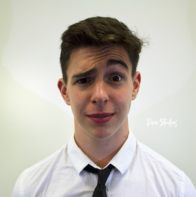 A portrait of Jake, they wear a white shirt and a black tie.