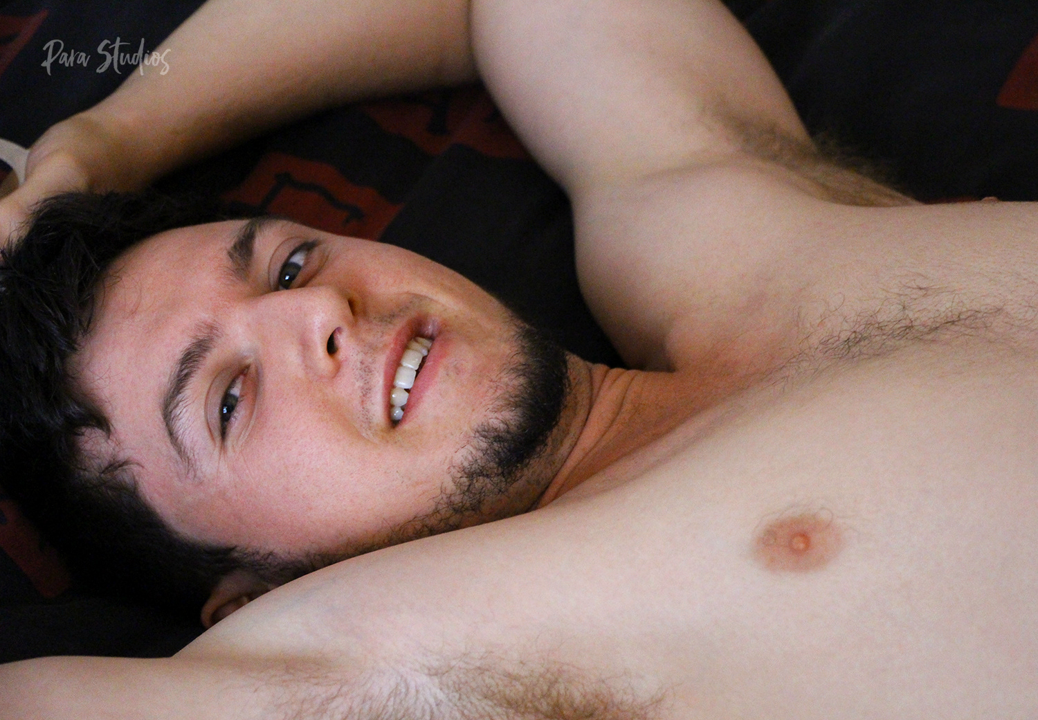 "Content". A man lies on a bed, is shirtless, and gazes at the camera.