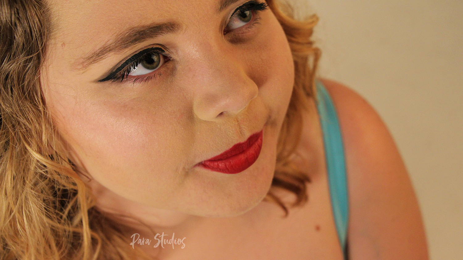 "Mused". A woman smiles and gazes upwards, she wears red lipstick.