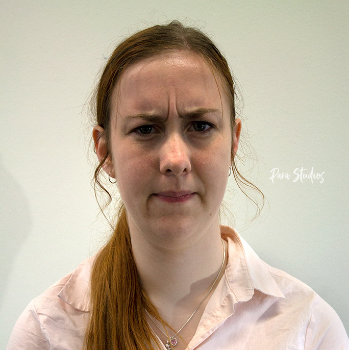 A portrait of Racket, they wear a pink blouse and their hair in a ponytail.