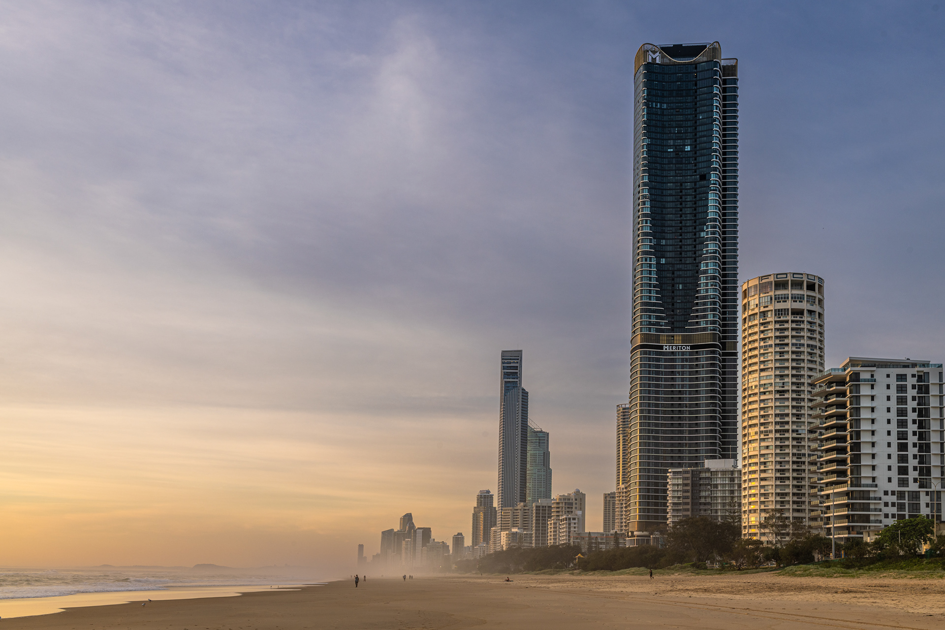 cross section of sandy beach at Surfers Paradise, Queensland, with monumental apartment towers on the upland side, reflecting first light sunrise