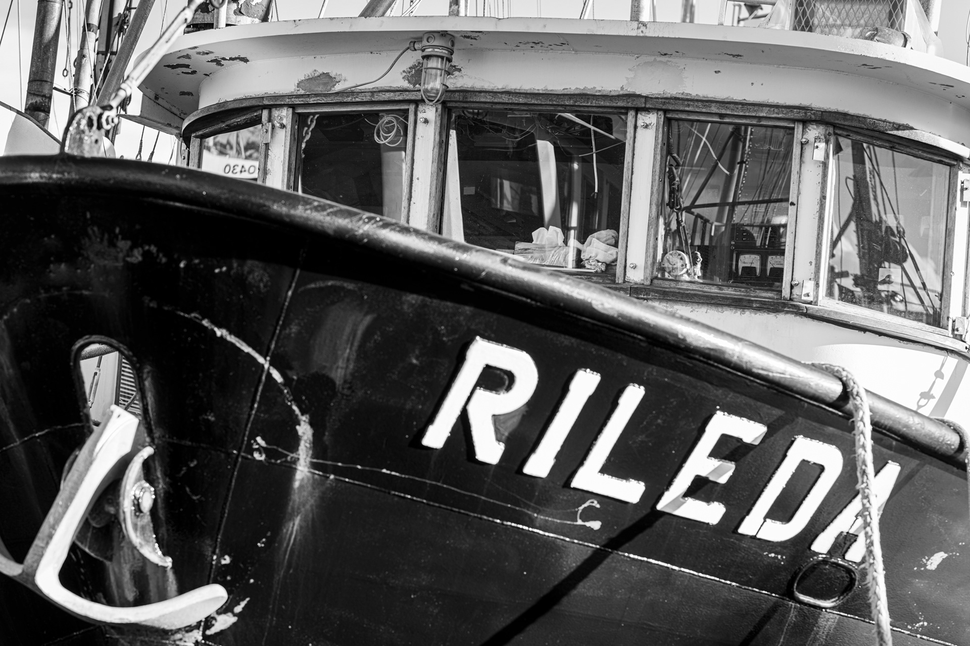 Closeup looking over the bow at the wheelhouse of a steel commercial fishing boat, monochrome