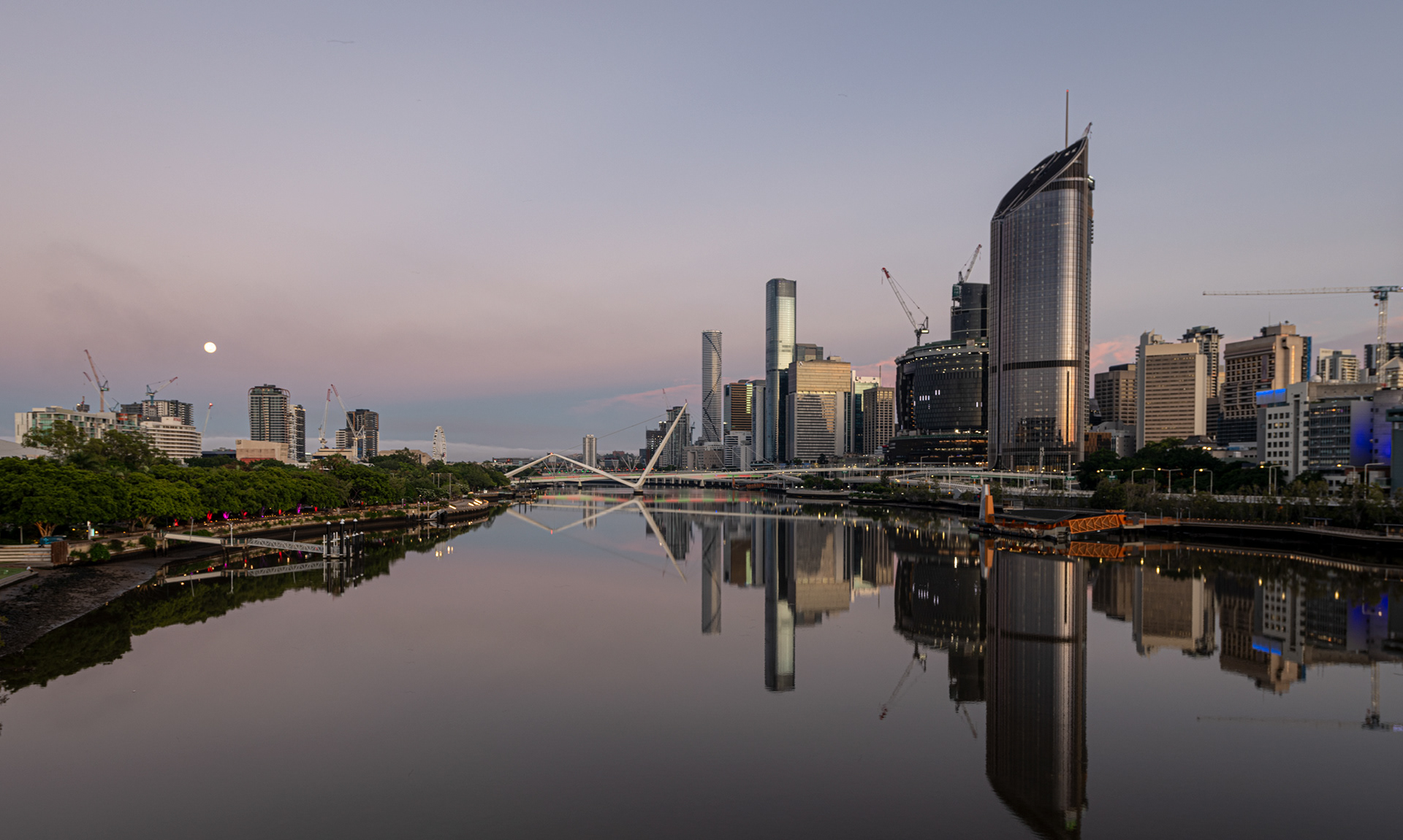 Brisbane River, Queensland, with calm waters reflecting the CBD buildings and riverfront parks at sunrise