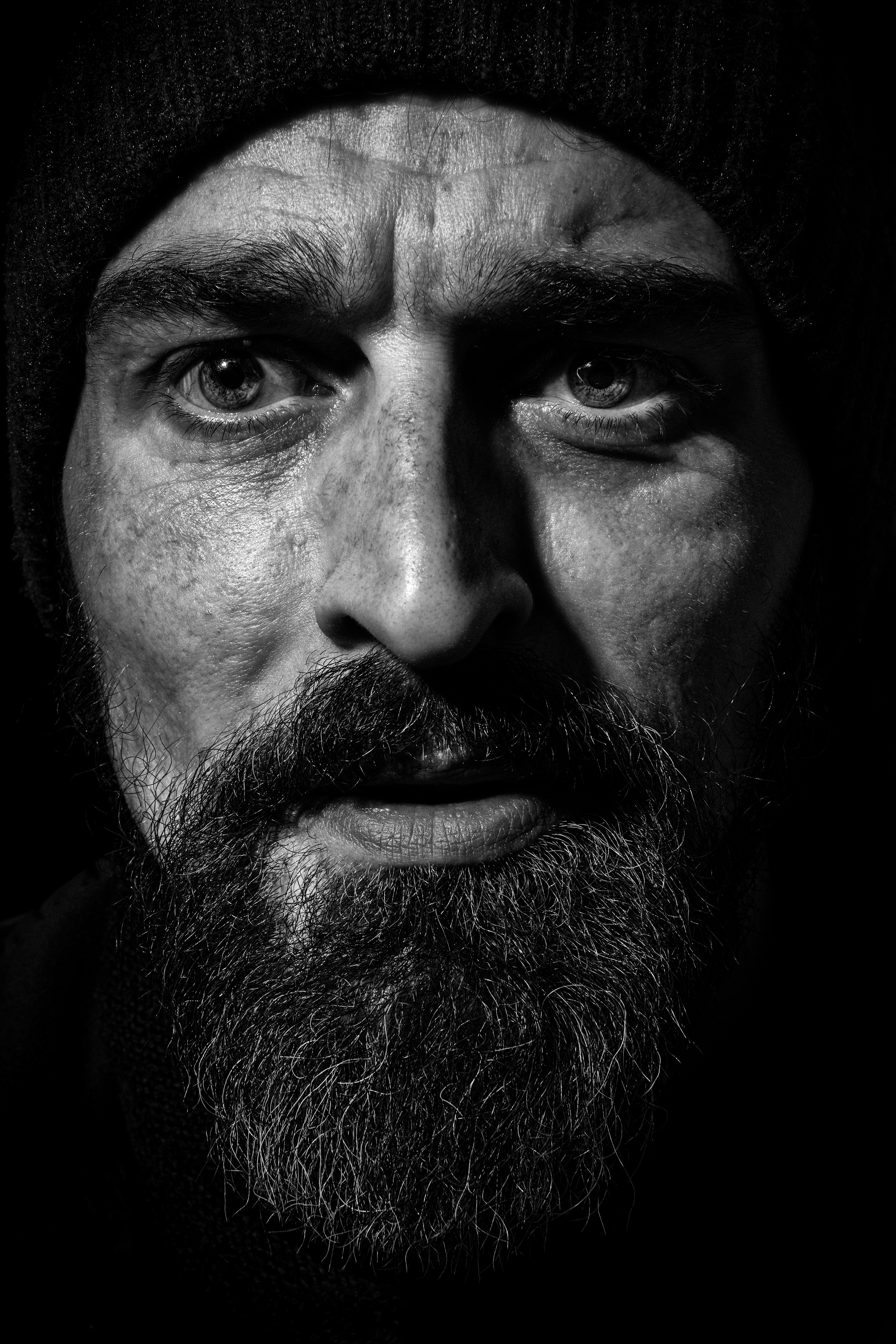 portrait noir et blanc d’un homme barbu avec éclairage latéral godox lux master contrasté, regard intense, réalisé à Trouville sur mer