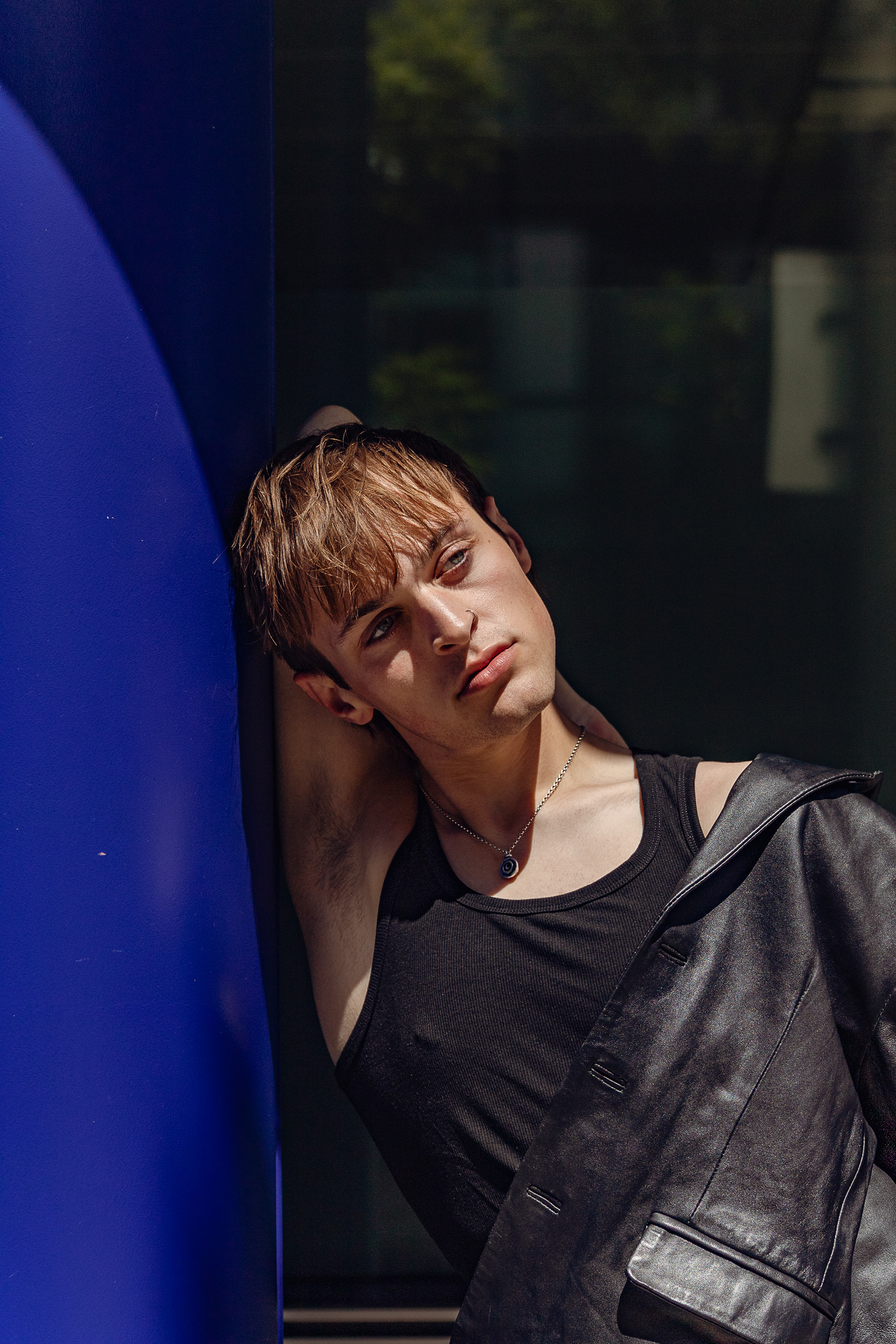 Man leaning against bright blue pillar close up
