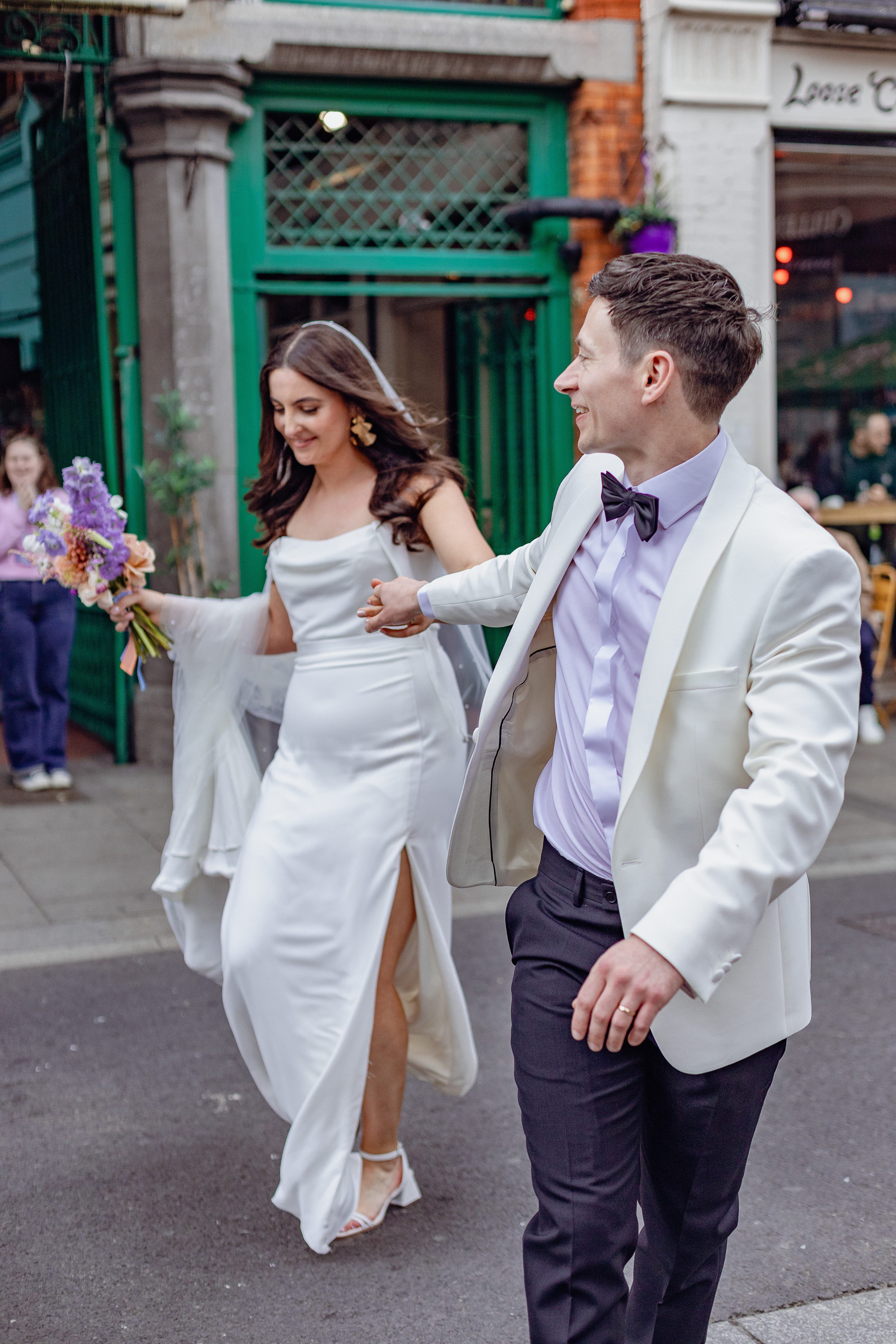 Wedding couple walk through the streets smiling
