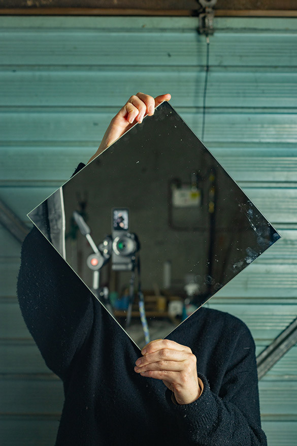 person holding a square shaped mirror in front of face