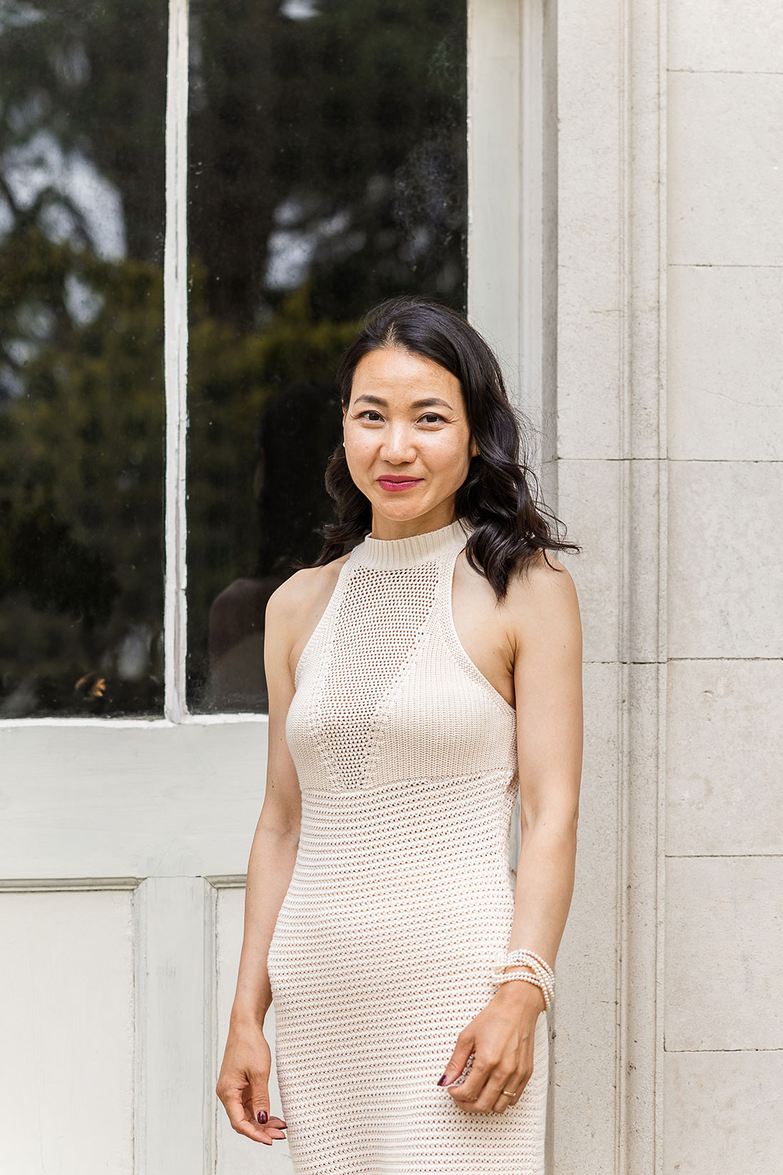 Bride in high neck cream dress standing in front of stone building
