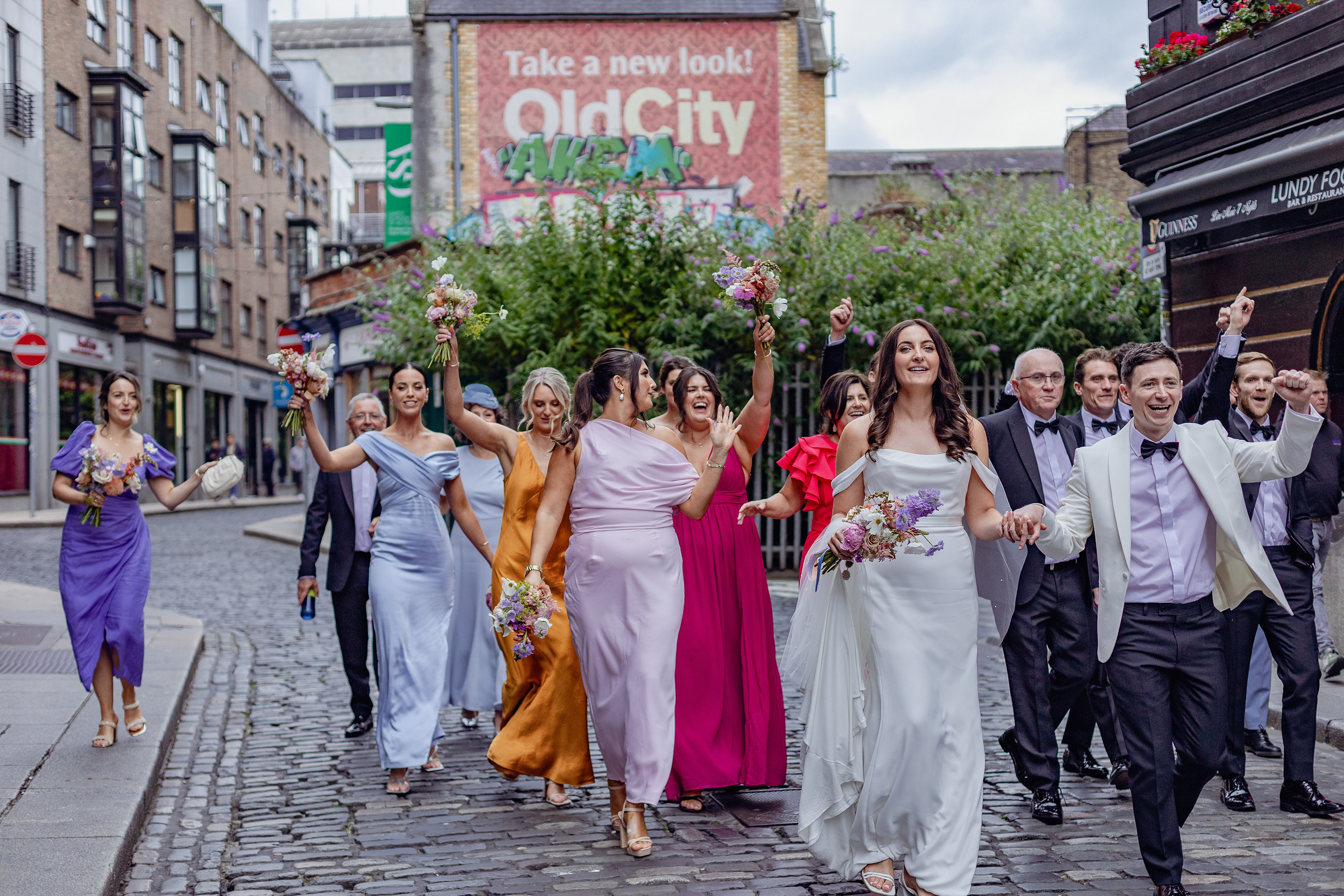 Whole wedding party walk down the street celebrating