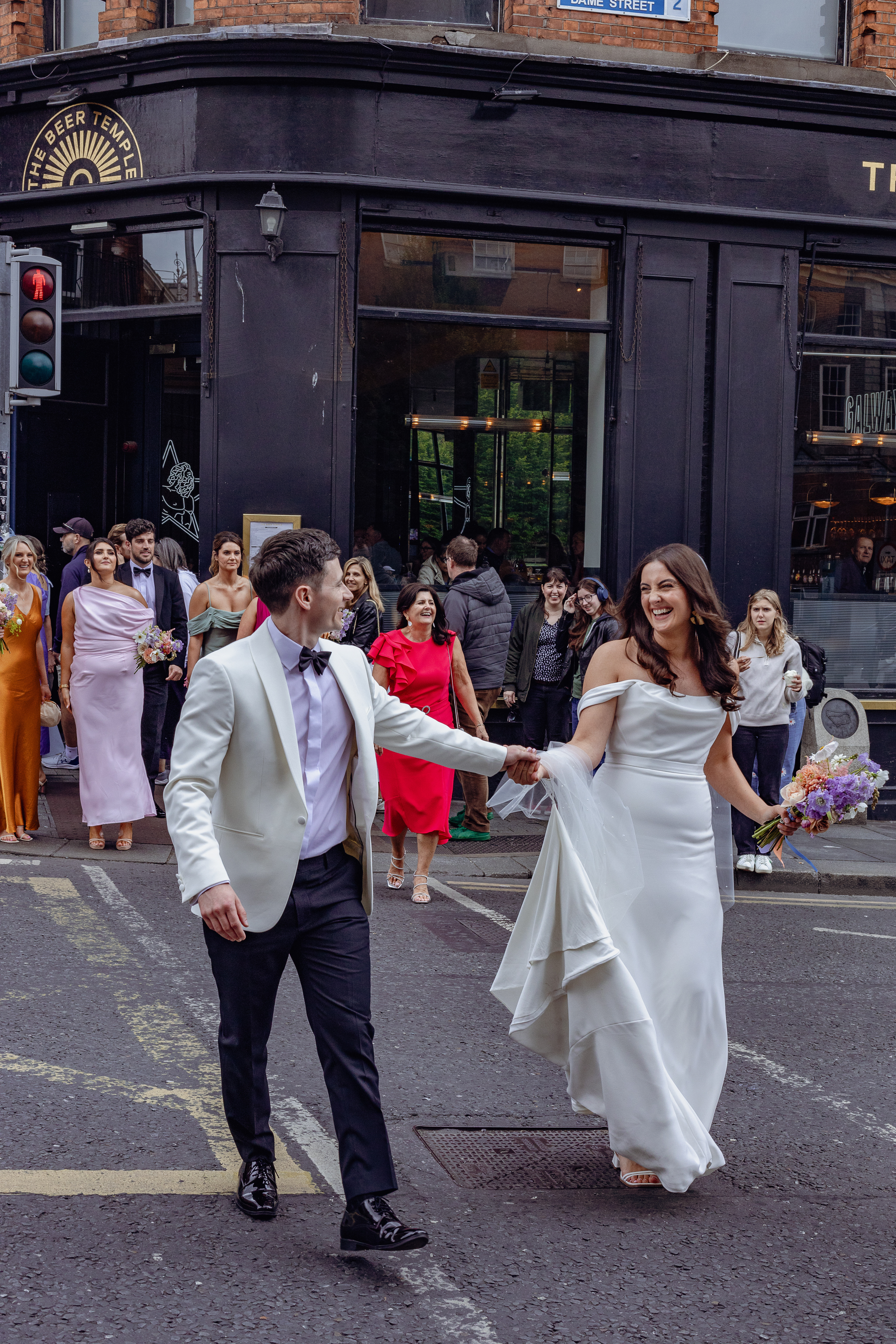Wedding couple cross the street smiling at each other